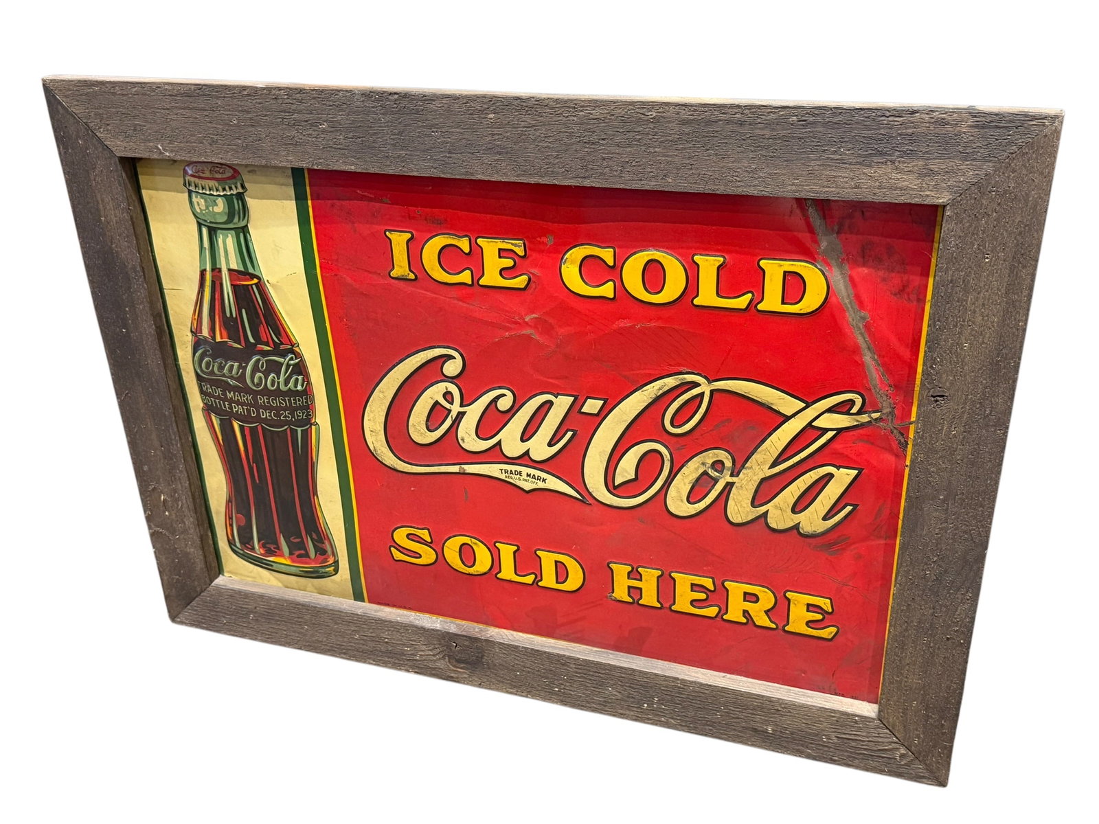 Early Coca Cola Advertising Sign in Frame: This is a vintage-style "Ice Cold Coca-Cola Sold Here" metal tin sign featuring a classic 1923 bottle graphic, custom-mounted inside a rustic reclaimed-wood frame. [1]Sign Details: Tin lithograph meta