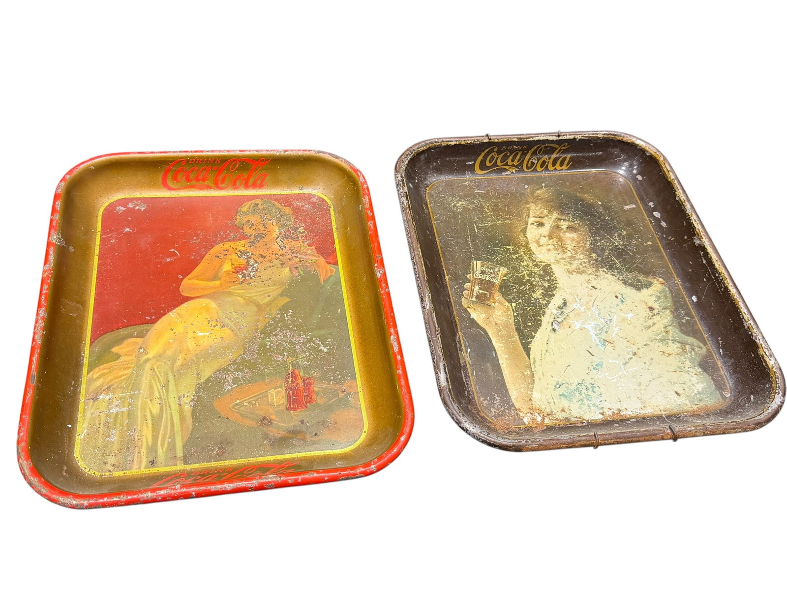 Lot of 2 Early Coca Cola Trays: These two vintage lithographed metal Coca-Cola serving trays from the 1930s showcase classic advertising art with visible authentic patina and surface wear. [1, 2]Tray DetailsLeft Tray (1936 Gown Desi