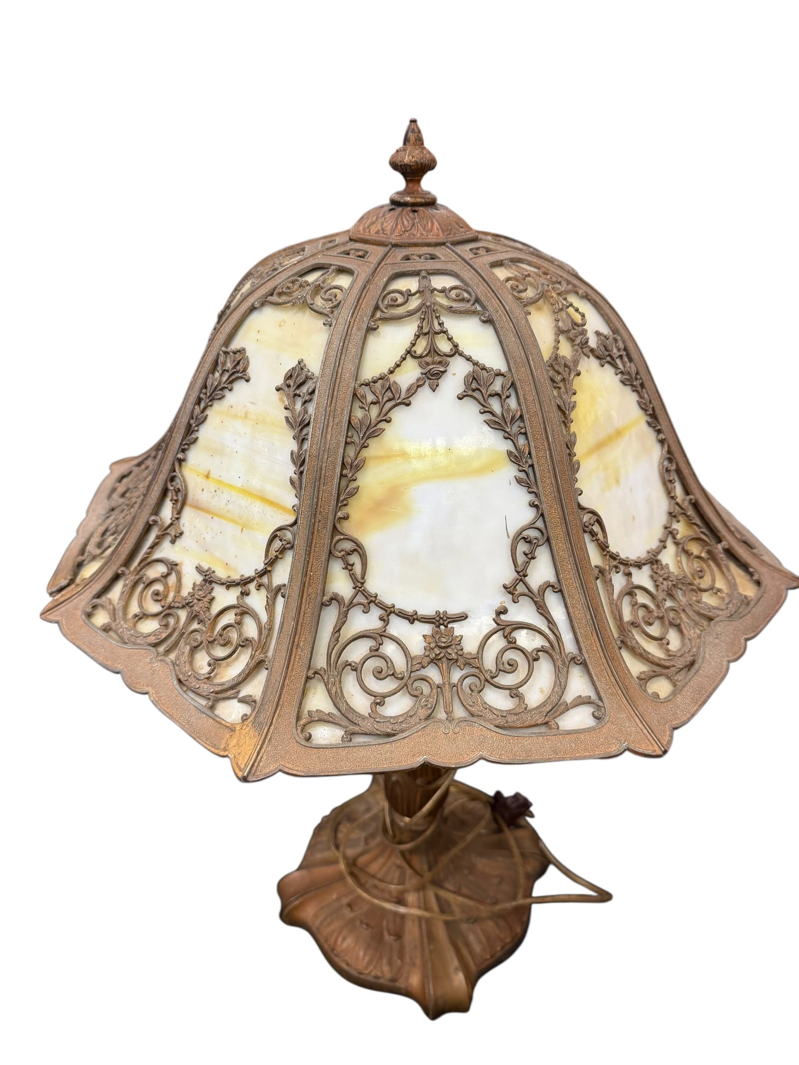 Slag Glass Lamp: Early 20th-Century Art Nouveau Slag Glass Lamp: This antique table lamp features curved caramel and white slag glass panels housed within an ornate, scrolling floral metal filigree frame and a
