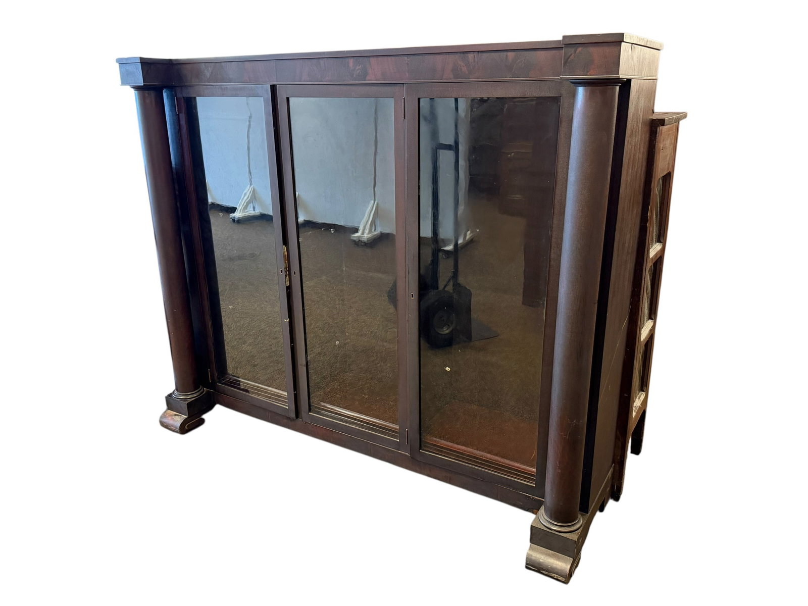 3 Door Mahogany Bookcase: This piece of furniture is an American Empire style triple glass-front bookcase (also referred to as a library case or display cabinet), dating roughly from the late 19th century to early 20th