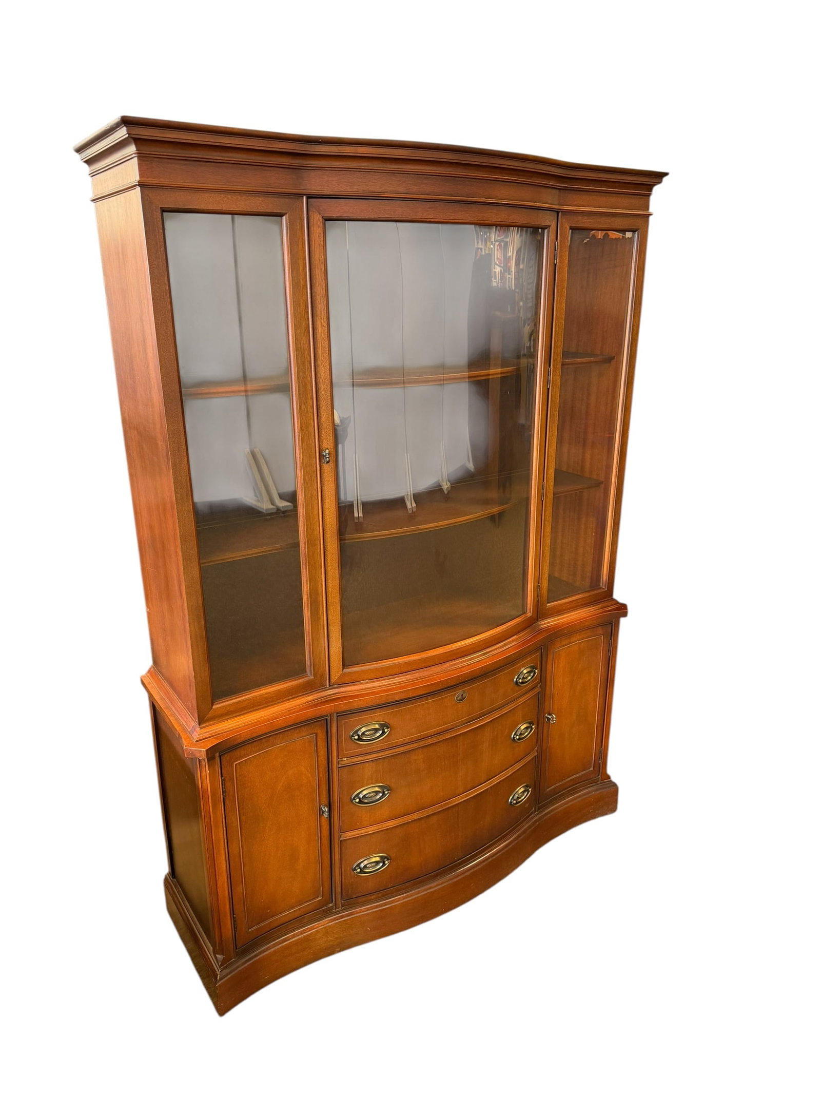 Bassett Furniture Mahogany China Cabinet: This piece of furniture is a 1950s Bassett Monticello mahogany serpentine bow front china cabinet. Built by Bassett Furniture Industries, this vintage hutch blends a Mid-Century manufacturing era