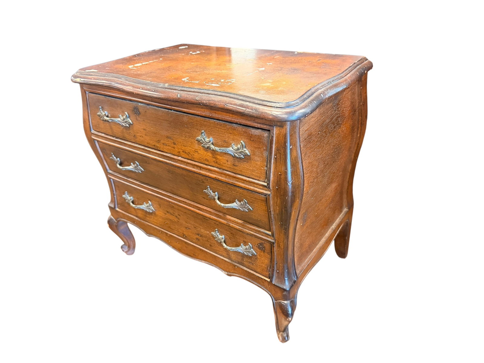 Miniature 3 Drawer Bombay Chest: This piece of furniture is a vintage French Country style small bombé chest or nightstand, featuring an outwardly bowed, swelling silhouette, ornate brass drawer pulls, a contoured top, and elegant