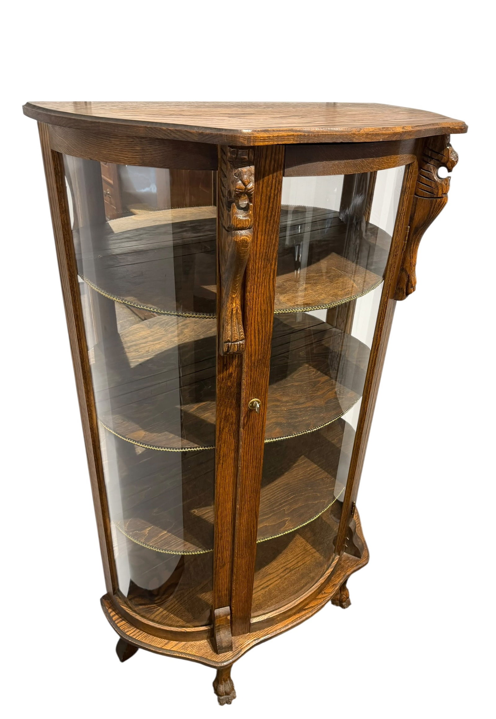 Oak Bowfront China Cabinet: This piece of furniture is a circa 1900 American antique quarter sawn tiger oak curio or china cabinet. [1]Key Features & Style IdentificationStyle Era: Late Victorian into the Edwardian period (c.
