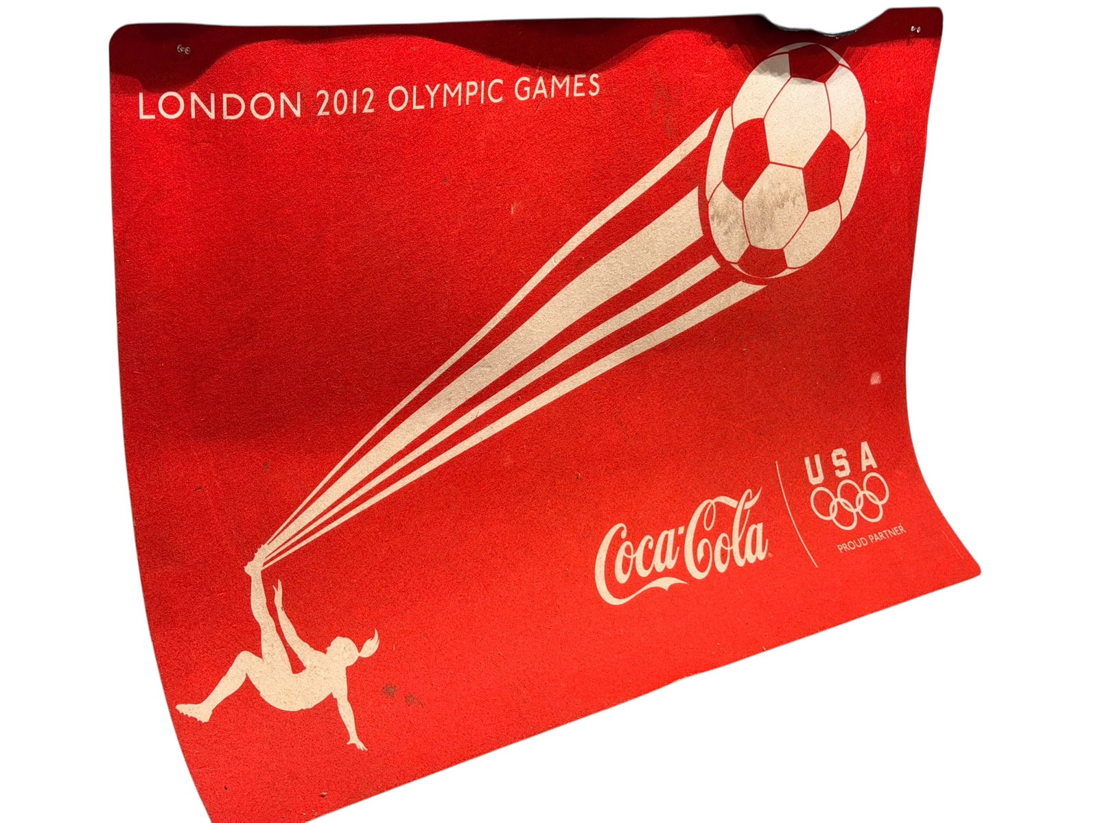 London 2012 Olympics Coca Cola Mat: This appears to be a promotional or display sign from Coca-Cola celebrating Team USA at the London 2012 Olympic Games. [1]Design: Features a red background with a graphic of an athlete kicking a
