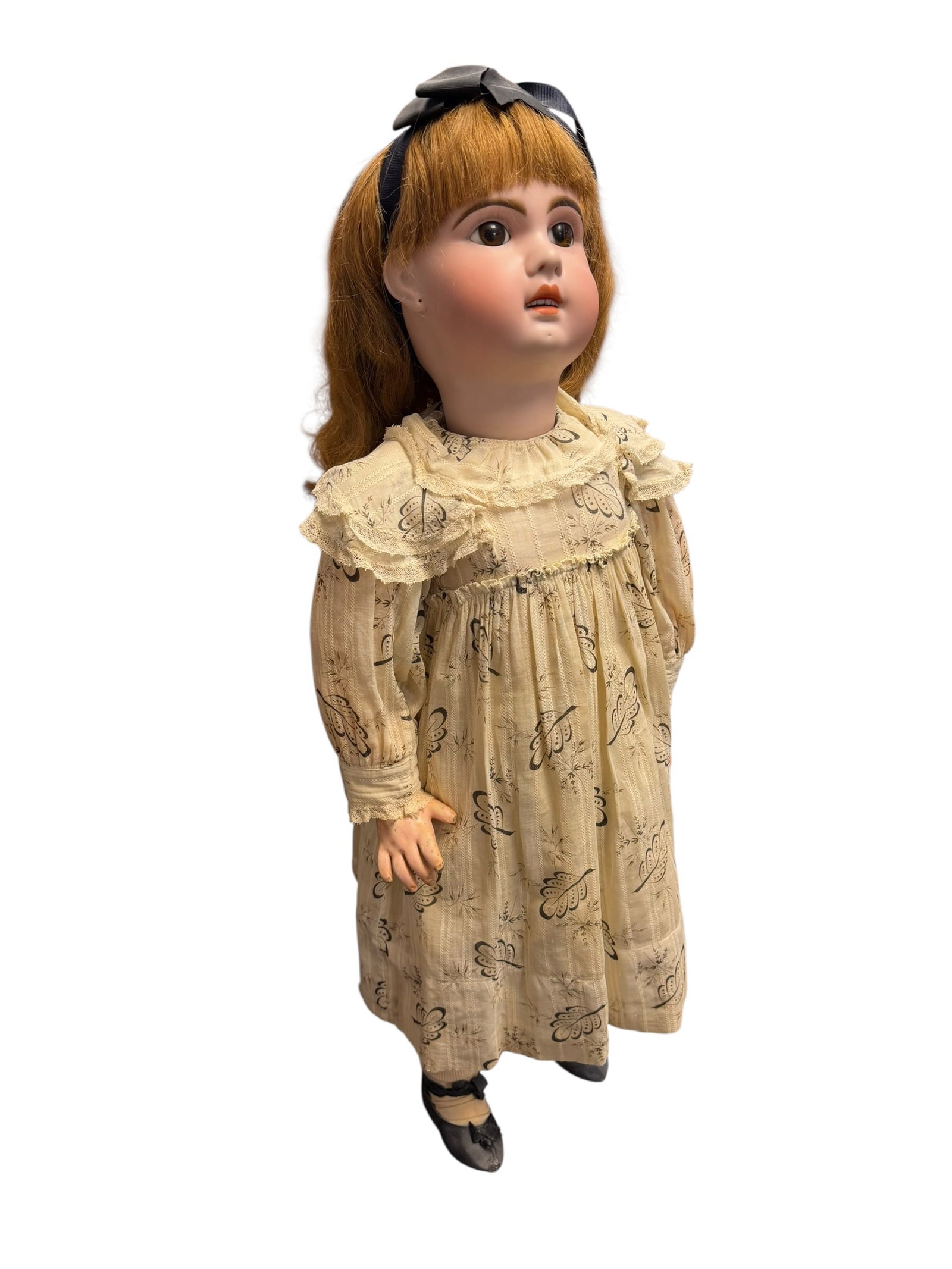 Bisque Head Doll With white Dress: antique bisque-head doll featuring reddish-brown hair and wearing a cream-colored patterned dress with a lace-trimmed collar. [1, 2]Overview of Antique Bisque DollsHead Material: Made from unglazed