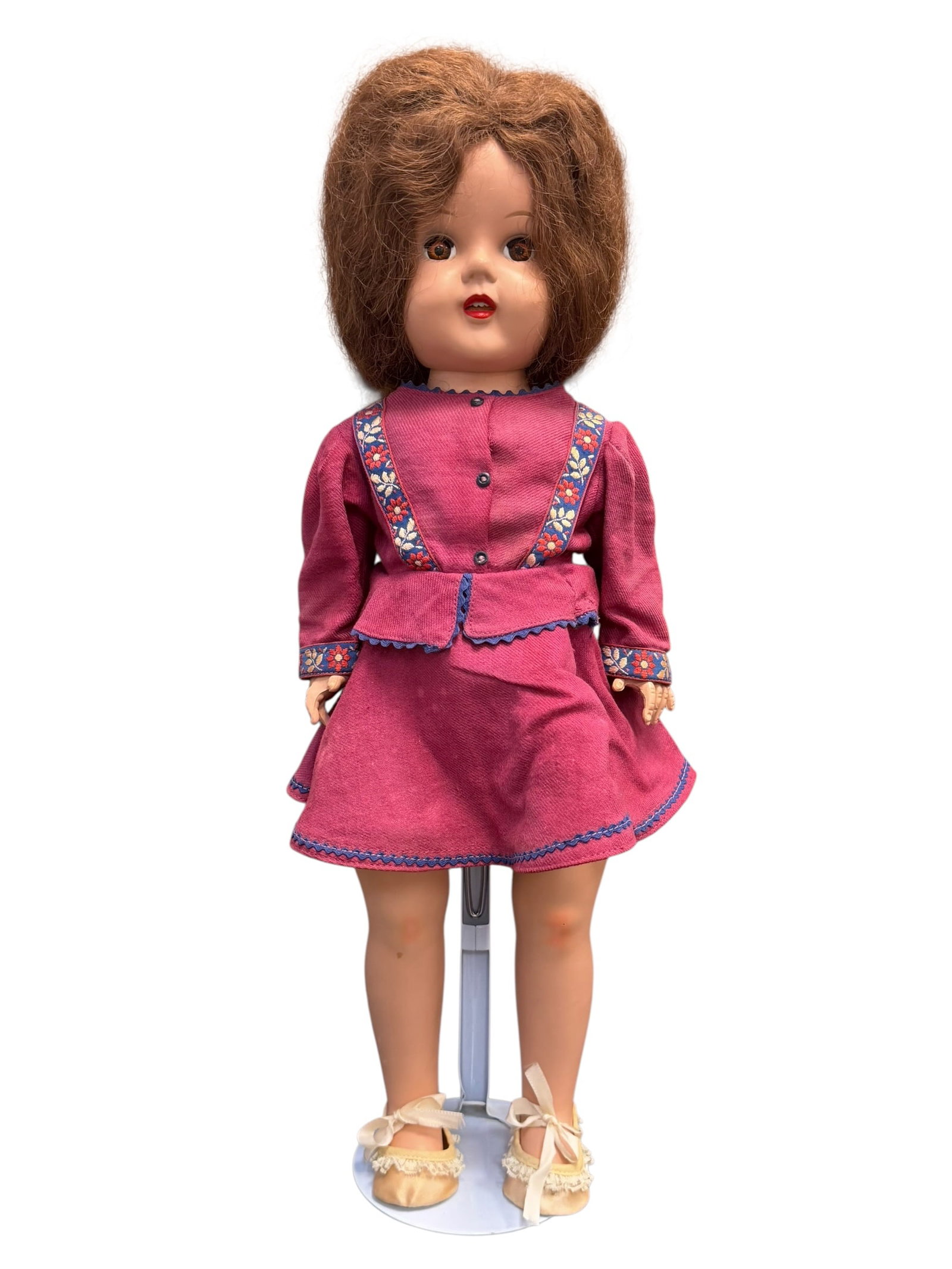 Vintage Composition Doll: vintage mid-century hard plastic walking doll, resembling popular 1950s models like Ideal's Saucy Walker or American Character dolls, wearing a magenta two-piece dress with blue floral ribbon trim and