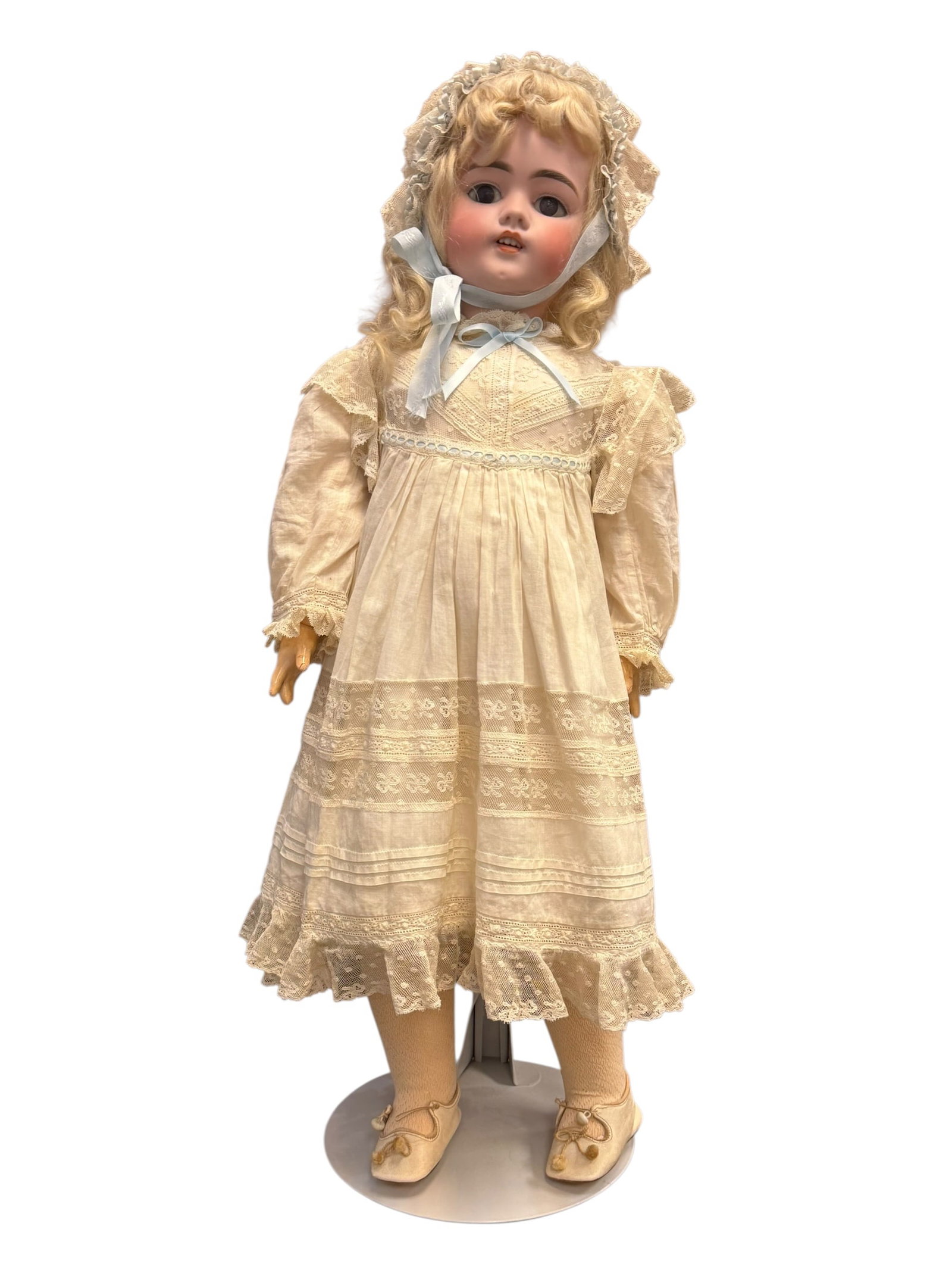 German Handwerck Bisque Head Doll: antique German bisque-head doll from the late 19th or early 20th century, featuring a painted porcelain face, a blonde curly wig, and a lace-trimmed cotton dress. [1, 2]Head: Made of bisque porcelain