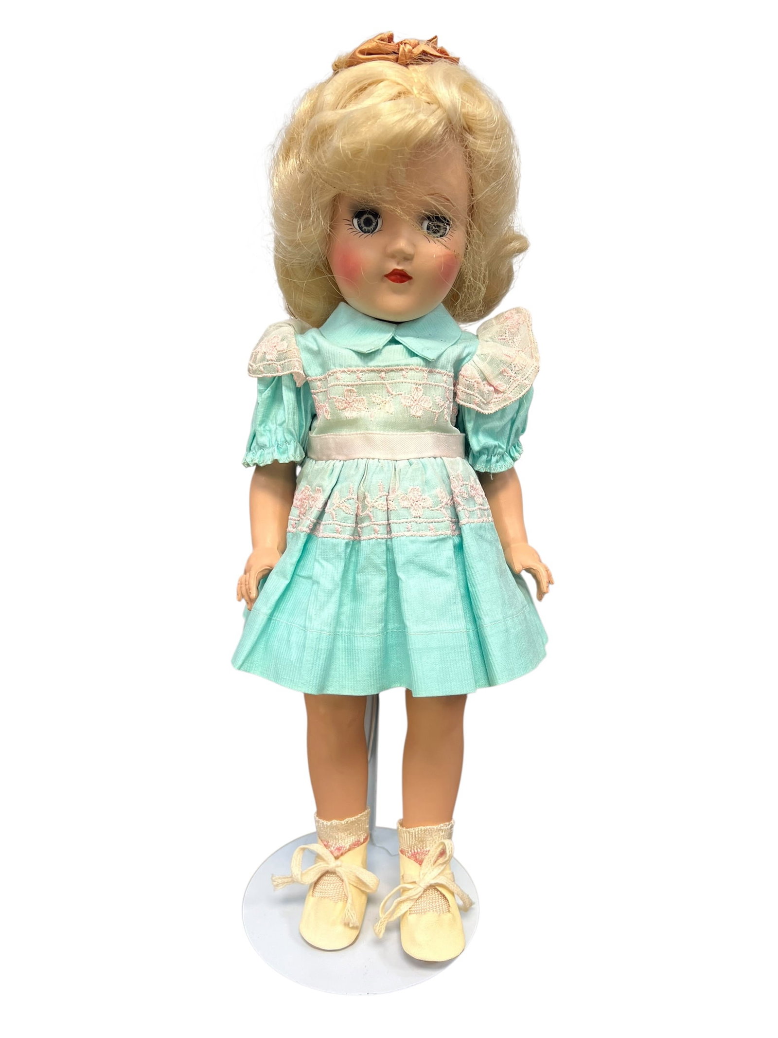 Ideal Vinyl Head Doll: vintage 1950s Ideal Toni hard plastic doll wearing a light blue dress with pink embroidery. [1]Key DetailsManufacturer: Produced by the Ideal Toy Company during the early 1950s.Material: Crafted from