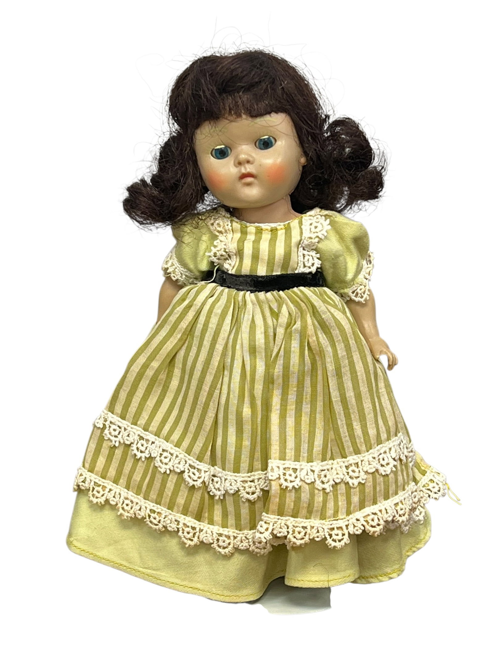 Vogue Plastic Doll: vintage hard plastic or composition doll with brown pigtails, blue sleep eyes, rosy cheeks, and a green-and-white striped dress trimmed with white lace. [1]Doll DetailsAppears to resemble