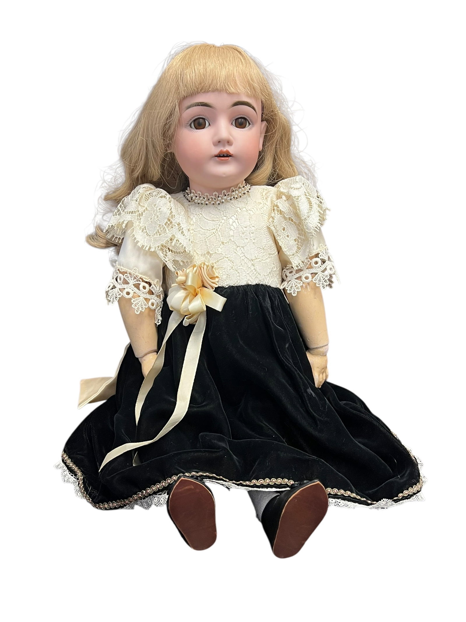 Germany Bisque Head Doll: antique bisque-head doll wearing a black velvet and cream lace dress. [1, 2]Key FeaturesHead: Made from tinted bisque porcelain with painted facial details and inset glass eyes.Hair: Styled with a