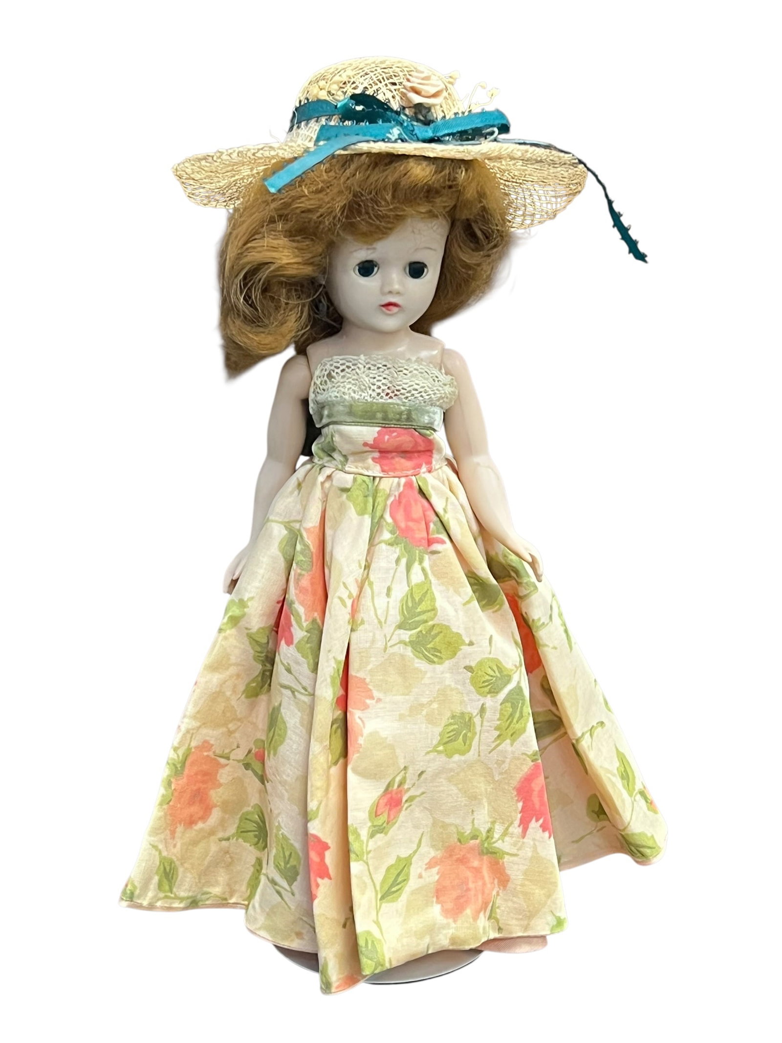 Vogue Vinyl Doll: vintage 1950s hard plastic fashion doll, resembling styles from brands like Ideal (such as Little Miss Revlon) or Vogue (such as Jill), wearing a floral-patterned dress and a straw hat with a blue rib