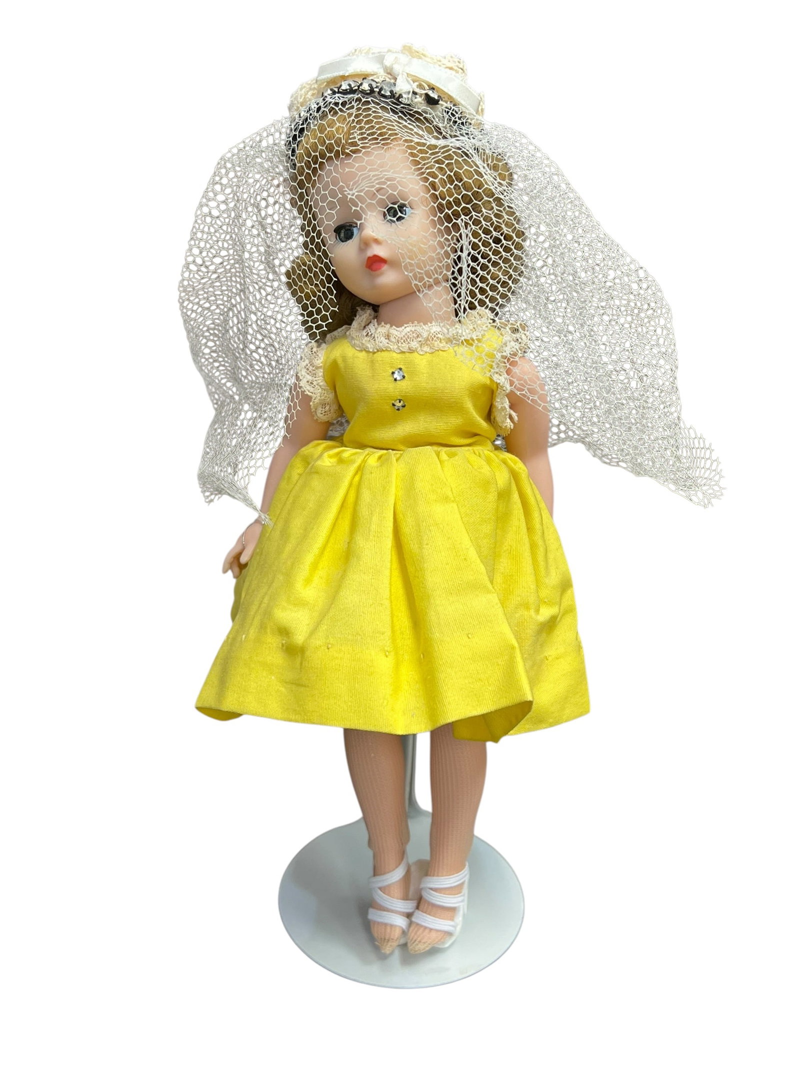 Madame Alexander Doll: vintage 1950s Madame Alexander Cissette fashion doll wearing a bright yellow dress and a white mesh veil. [1, 2, 3]Key FeaturesMaker: Created by the Madame Alexander Doll Company, famous for high-end