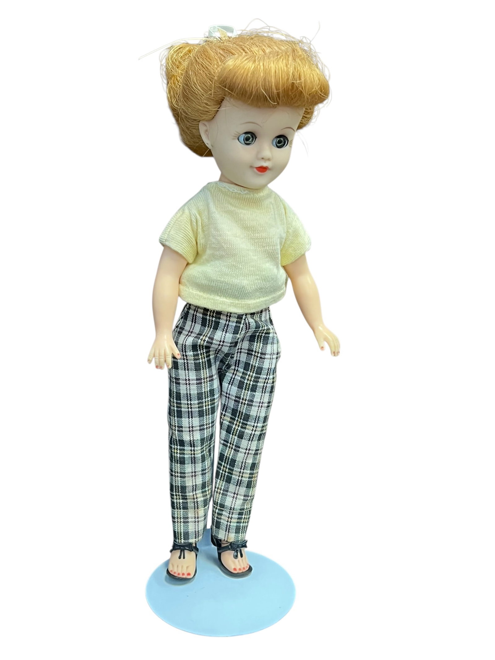 Vogue Vinyl Doll: This appears to be a vintage 1950s Vogue Jill doll featuring a blonde updo, sleep eyes, and a casual plaid pants outfit. [1, 2]Doll DetailsType: Mid-20th-century collectible fashion doll, resembling h