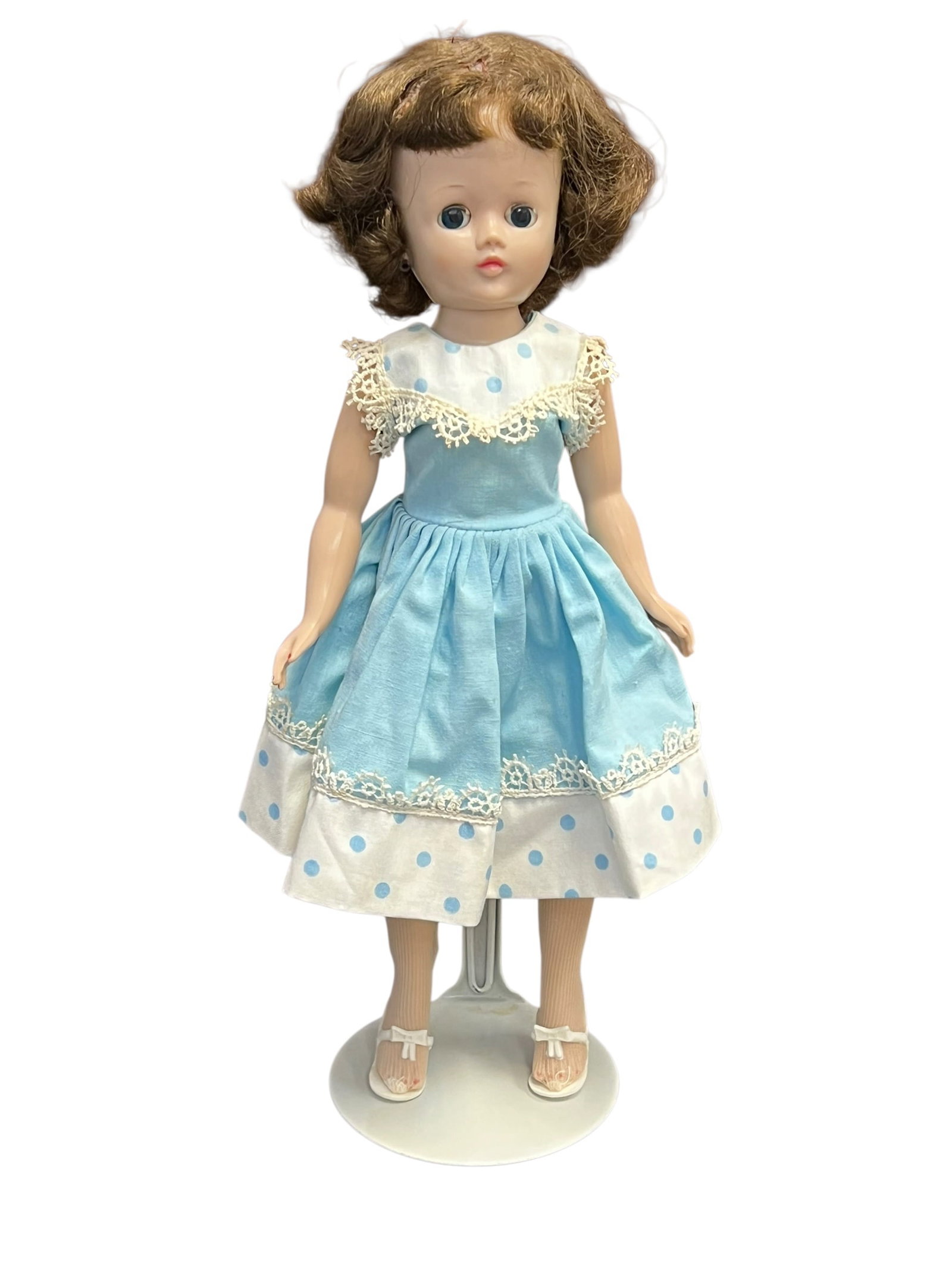 Vogue “Jill?? Plastic Doll: This is a vintage 1950s Ideal Toni doll, a highly popular and collectible hard-plastic doll manufactured by the Ideal Toy Company. [1]She is pictured wearing a classic light-blue party dress featuring