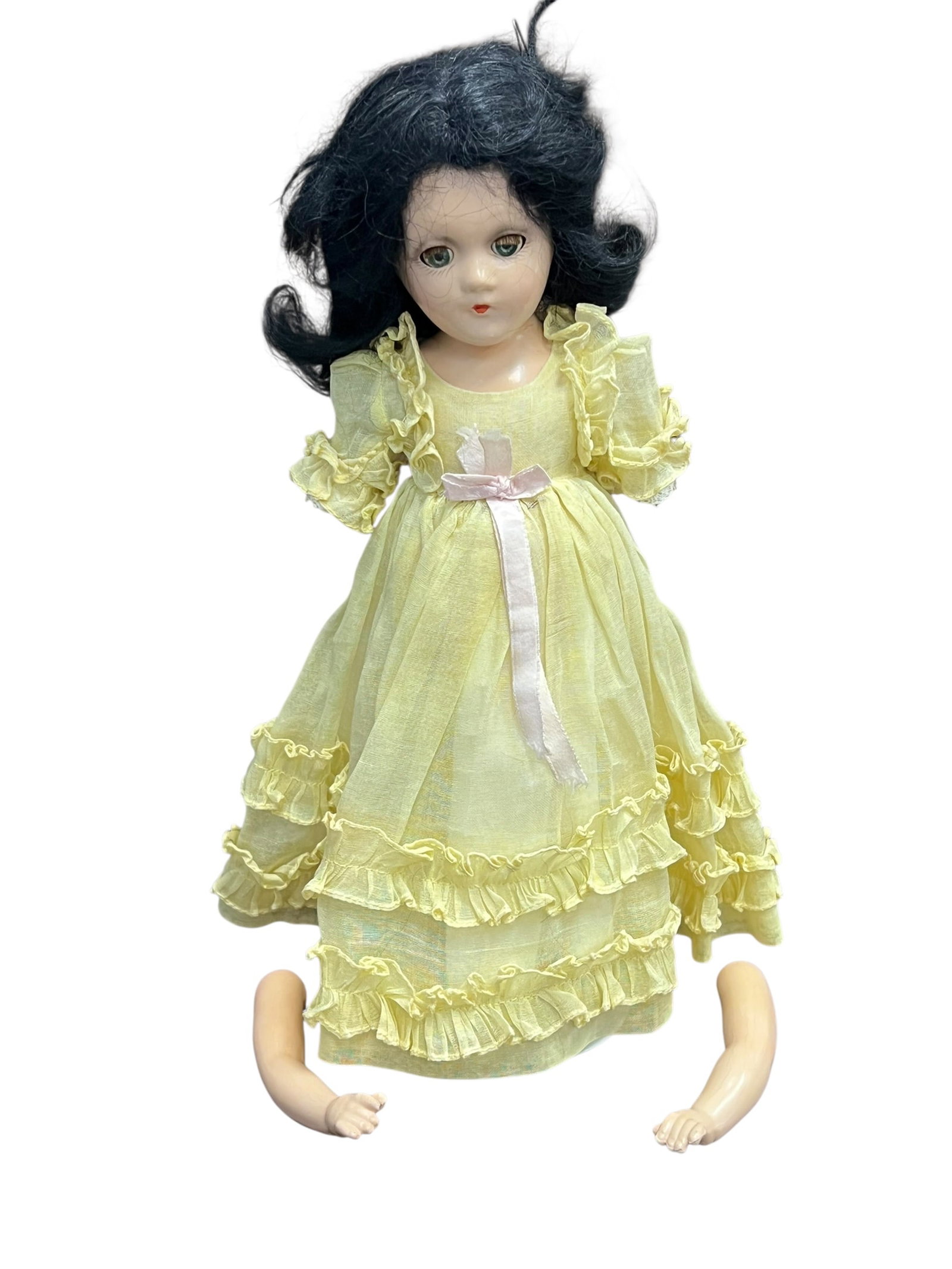 Madame Alexander “Scarlett Ohara?? Doll: vintage porcelain or composition doll with dark curly hair, green eyes, and a pale yellow ruffled dress tied with a pink ribbon.It appears to resemble a classic collectible doll style, possibly from