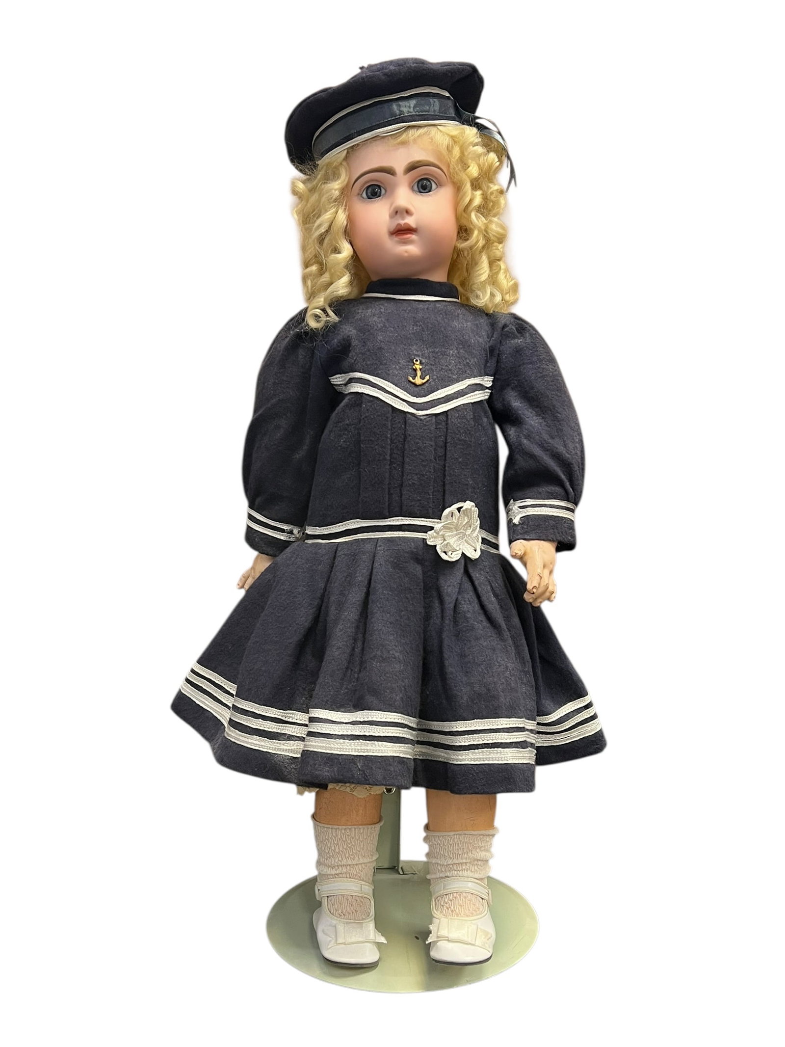 Bisque Head Doll: antique bisque doll elegantly styled in a classic navy blue sailor dress with contrasting white trim. It features a molded face, sculpted features, curly blonde hair, and a matching mariner cap.