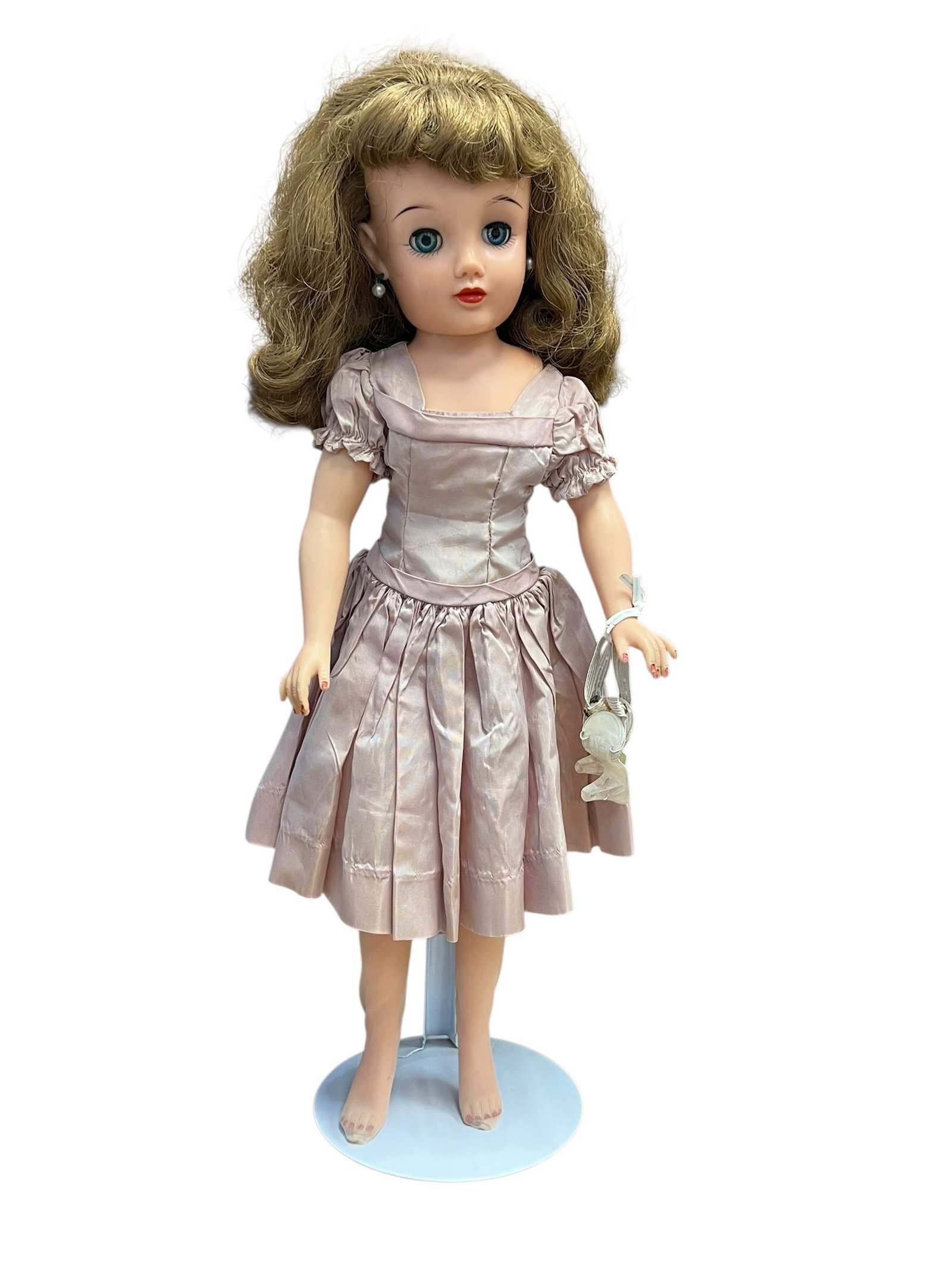 Ideal Revlon Vinyl Doll: vintage 1950s Ideal Miss Revlon fashion doll wearing a pink satin party dress. [1]Key FeaturesFace and Hair: Medium-length curly brown hair, clear blue sleep eyes, and small pearl earrings.Outfit: A