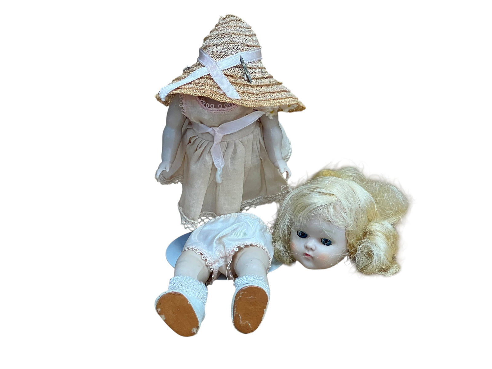 Vogue Plastic Doll: antique or vintage bisque-head doll disassembled into parts, including a dressed body, a separate lower body with socks and shoes, and a detached blonde-haired head.Doll Type: Bisque or porcelain doll