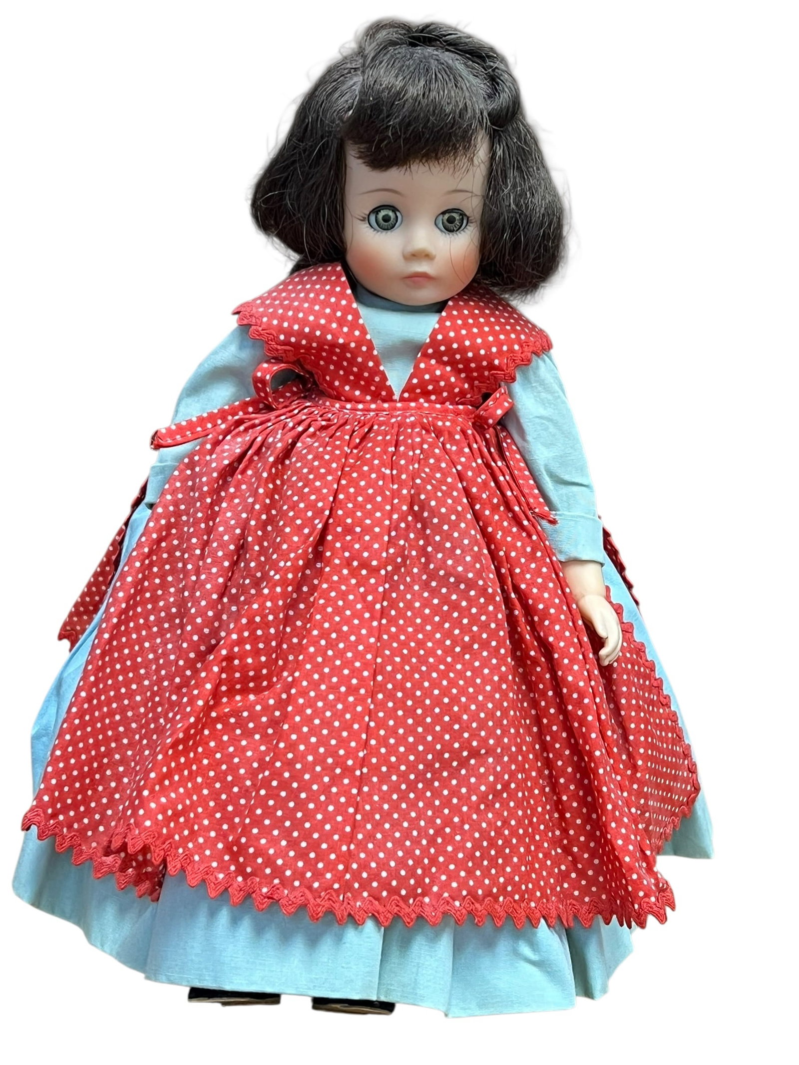 Alexander Vinyl Doll: This is a vintage Madame Alexander "Jo" doll from the classic Little Women series. She is instantly recognizable by her iconic bright blue dress paired with a red-and-white polka dot pinafore apron.