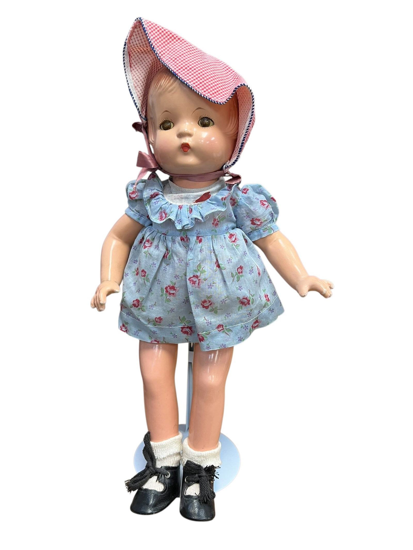 Fane Patsy John Composition Doll: This appears to be a vintage composition doll from the Effanbee Patsy family, likely dating from the 1930s, wearing a blue floral dress and a pink gingham sunbonnet. [1, 2]Doll FeaturesMaterial: