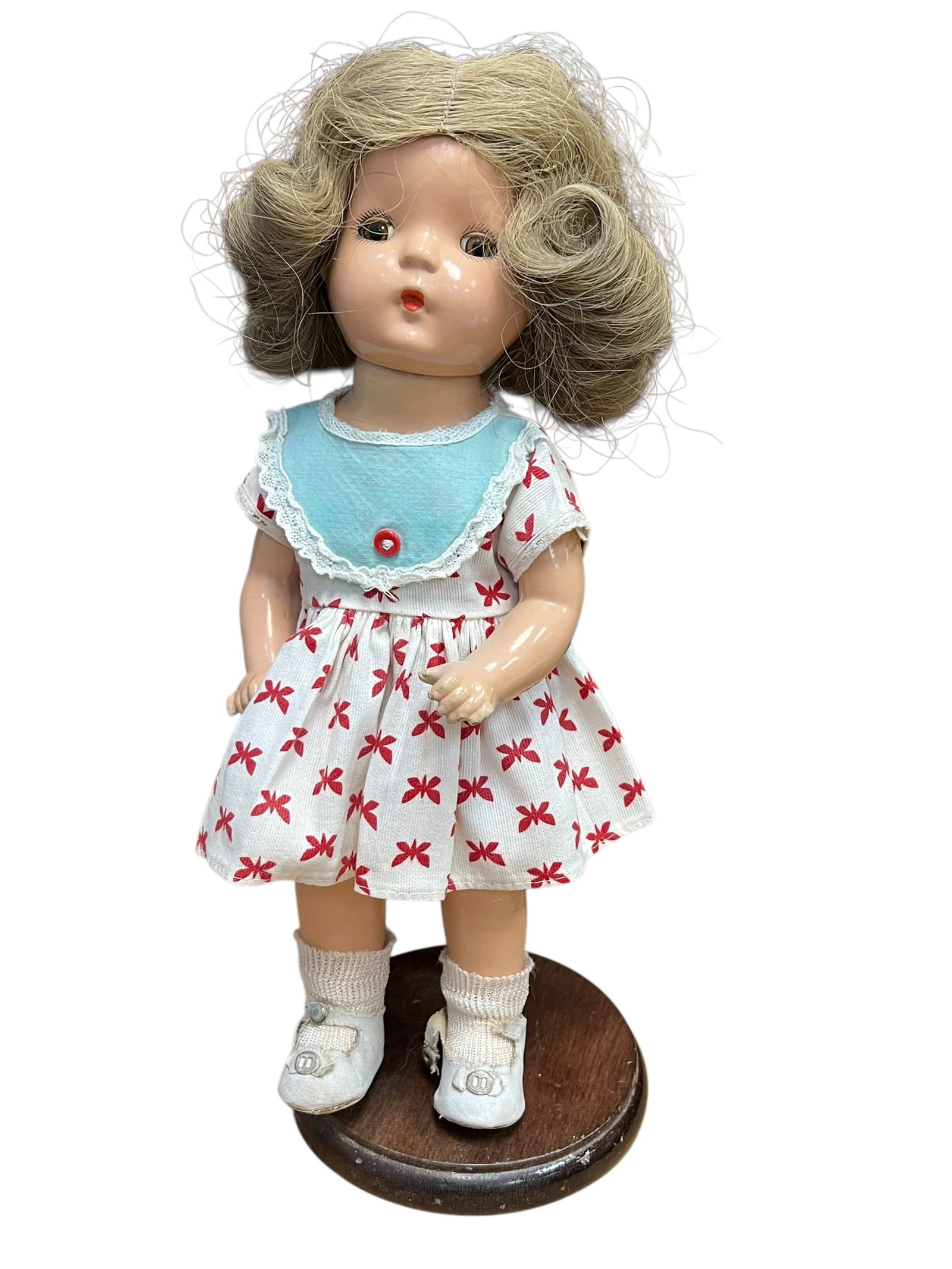Petit Porcelain/Composition Doll: vintage 1930s Ideal Shirley Temple composition doll featuring characteristic curly blonde hair, sleep eyes, and a patterned dress with a blue collar. [1, 2, 3]Doll DetailsMaterial: Composition (a mold
