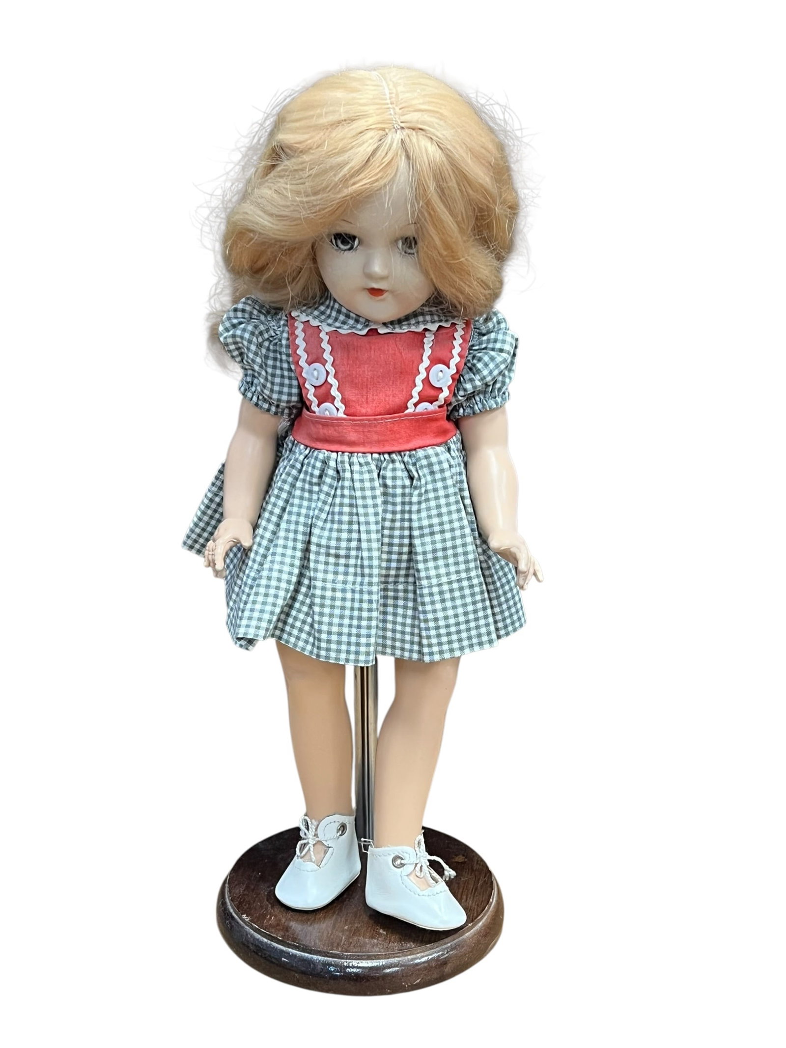 Ideal P-90 Doll: vintage hard plastic doll, likely a 1950s Ideal Toni Doll, featuring blonde wavy hair, sleep eyes, and a green gingham dress with a red bodice and white button accents. [1, 2]