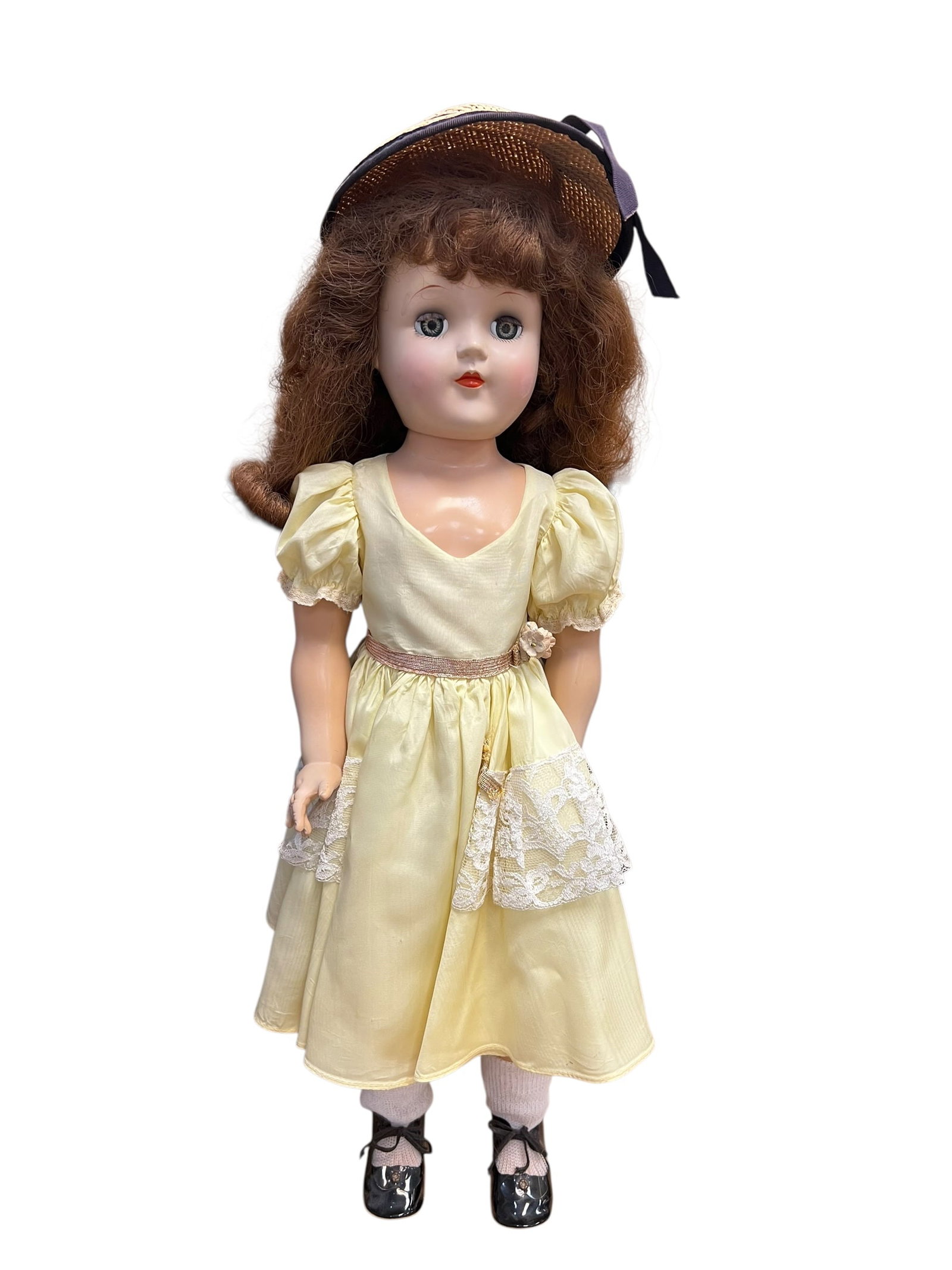 Ideal Genuine Toni Doll: This image appears to show a vintage 1950s hard plastic Ideal "Toni" doll wearing a yellow dress and a straw hat. [1, 2]Manufacturer: Produced by the Ideal Toy Corporation, famously used to promote