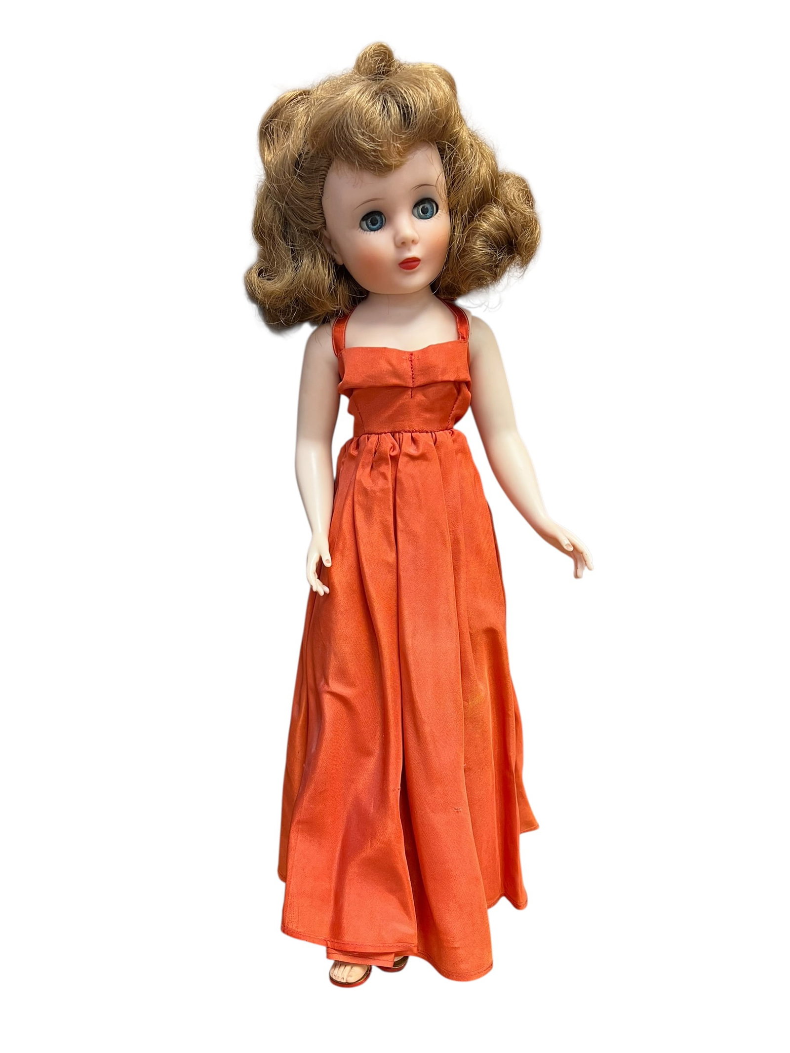 American Character Doll: vintage 1950s fashion doll, resembling a Vogue Jill or Ideal Miss Revlon doll, wearing a long orange sleeveless dress. [1, 2]The doll features painted facial details, blue sleep eyes, and styled light