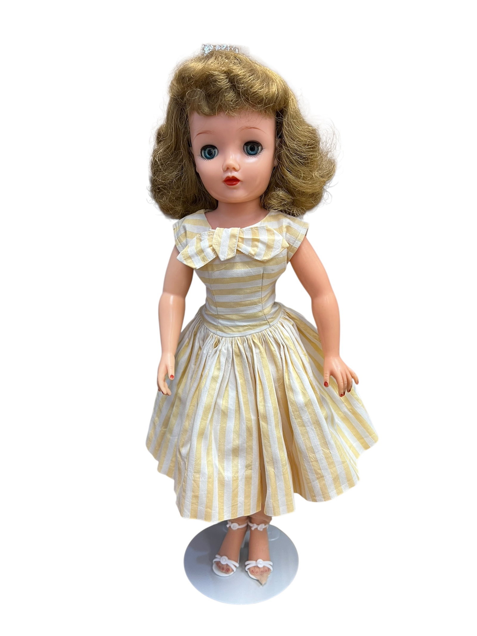 Ideal Vinyl Doll: This is a vintage 1950s Ideal Miss Revlon doll. Produced by the Ideal Toy Company, she stands out with her characteristic adult fashion silhouette, sleep eyes, rooted hair, and high-heel feet. [1, 2, 