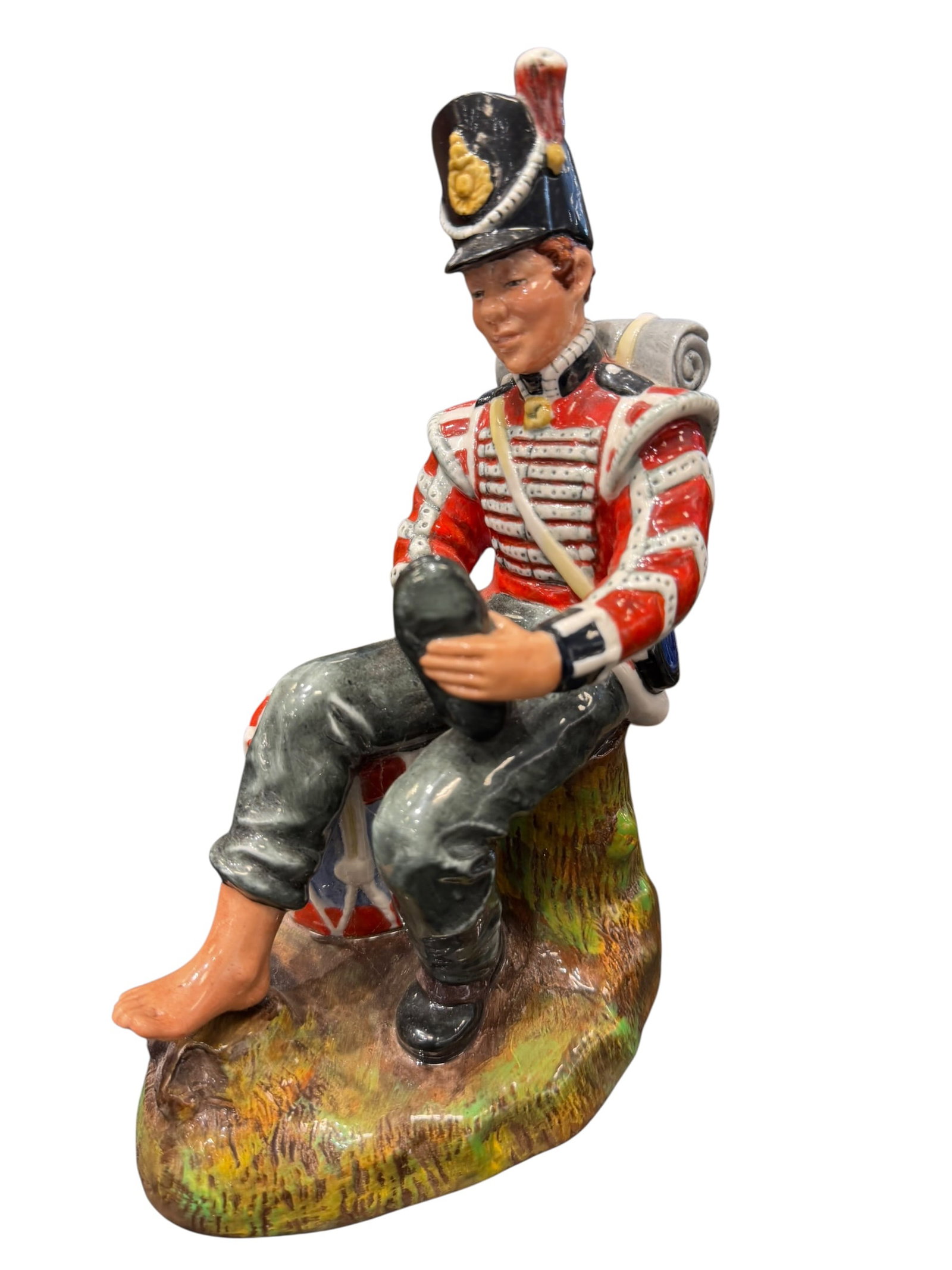 Royal Doulton “Drummer Boy?? Porcelain Figurine: Royal Doulton “Drummer Boy” HN 2679 hand-decorated bone china figurine, copyright 1975. Depicts a young military drummer resting on a tree stump while removing or adjusting one boot, with his 