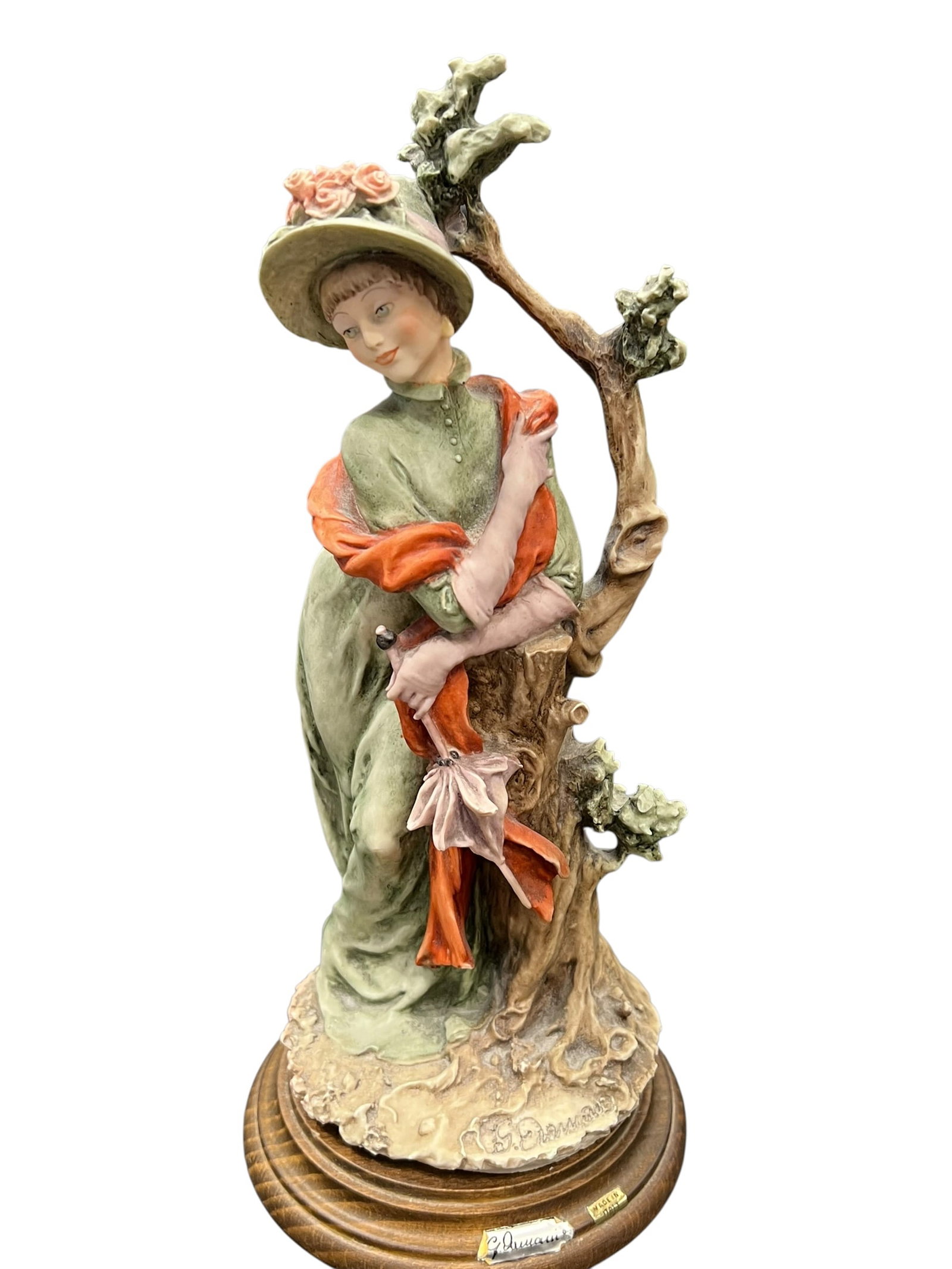 Capodimonte-Style Italian Porcelain Lady Figurine, Signed C. Duran: Decorative Italian porcelain figurine of an elegantly dressed lady, depicted leaning against a naturalistically modeled tree trunk. She wears a flowing sage-green gown, broad-brimmed hat decorated