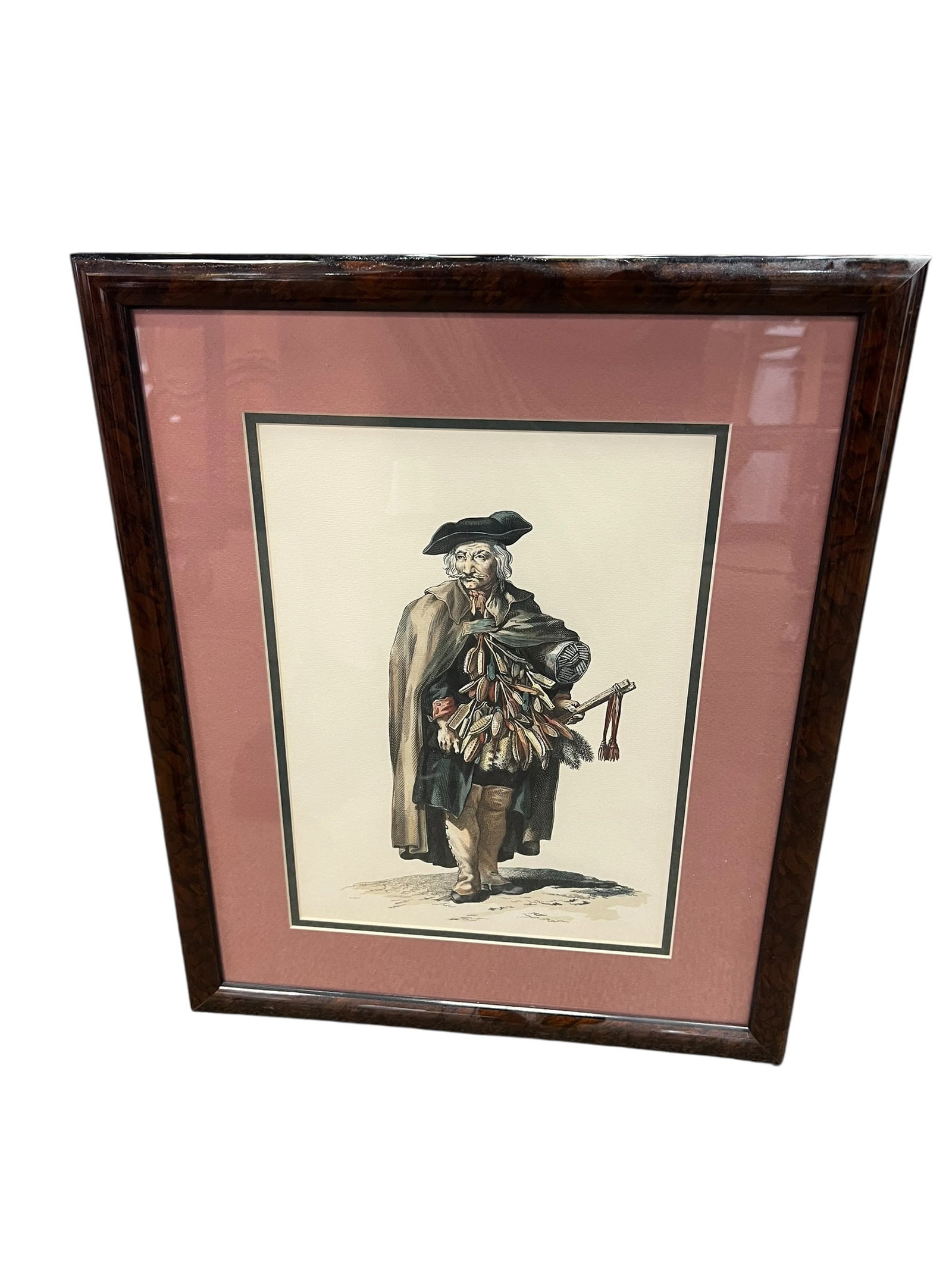 Framed Hand-Colored European Street Vendor / Traveling Merchant Print: Decorative framed hand-colored occupational costume print depicting a male street vendor or traveling merchant dressed in traditional period attire. The figure wears a broad hat and long cloak and car