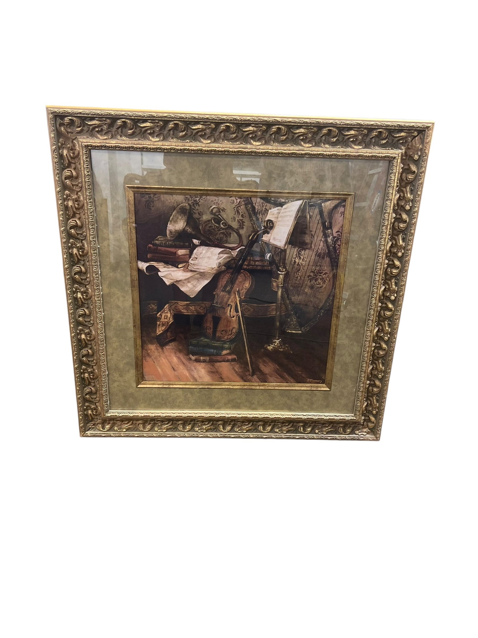 O’Flannery Musical Still Life Print – Violin, Harp & Sheet Music in Ornate Gilt Frame: Decorative framed musical still life signed “O’Flannery” at the lower right. The composition depicts a violin and bow, harp, sheet music, books and other musical elements arranged in a richl