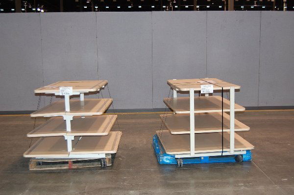 4 Tier Apparel Table and 4 Way Islanders: Two 4 Tier Apparel Tables with pull out shelves 48x45x35 Weight 665 on two pallets. One table is missing pull out board underneath top shelf for workspace. (Six) 4 Sided Pegboard Display Racks 30x