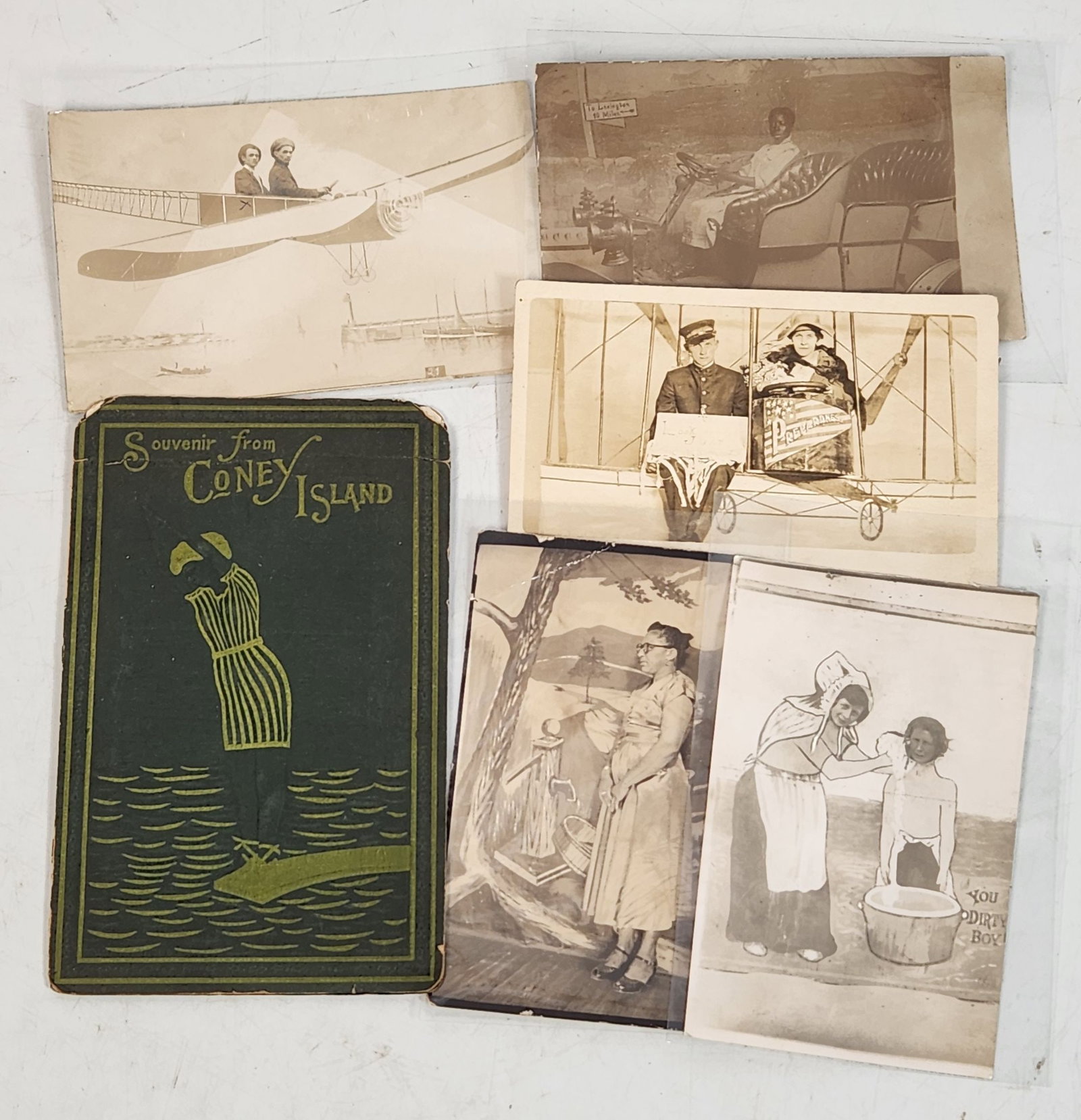 Vintage Coney Island Souvenir Booklet & Novelty Photo Postcards: This lot features a collection of vintage photographs and postcards. Included is a souvenir booklet from Coney Island, showcasing a stylized design. Several postcards depict people in staged or novelt