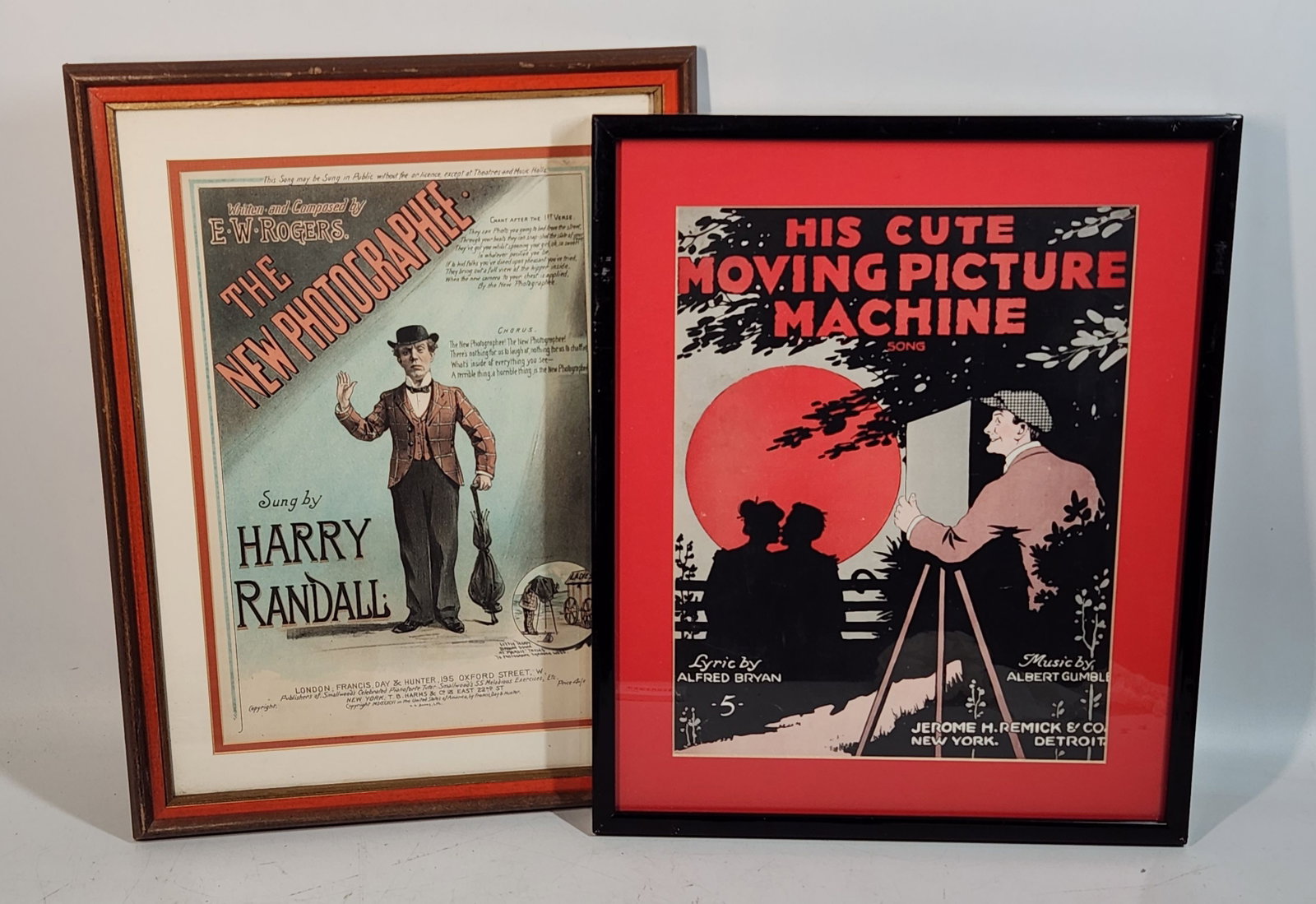 Antique Framed Song Covers - "The New Photographee" & "Moving Picture": Two framed antique song covers. The first is "The New Photographee" by E.W. Rogers, sung by Harry Randall, in a brown and red frame. The frame measures approximately 18.75" tall and 13.75" wide. The s