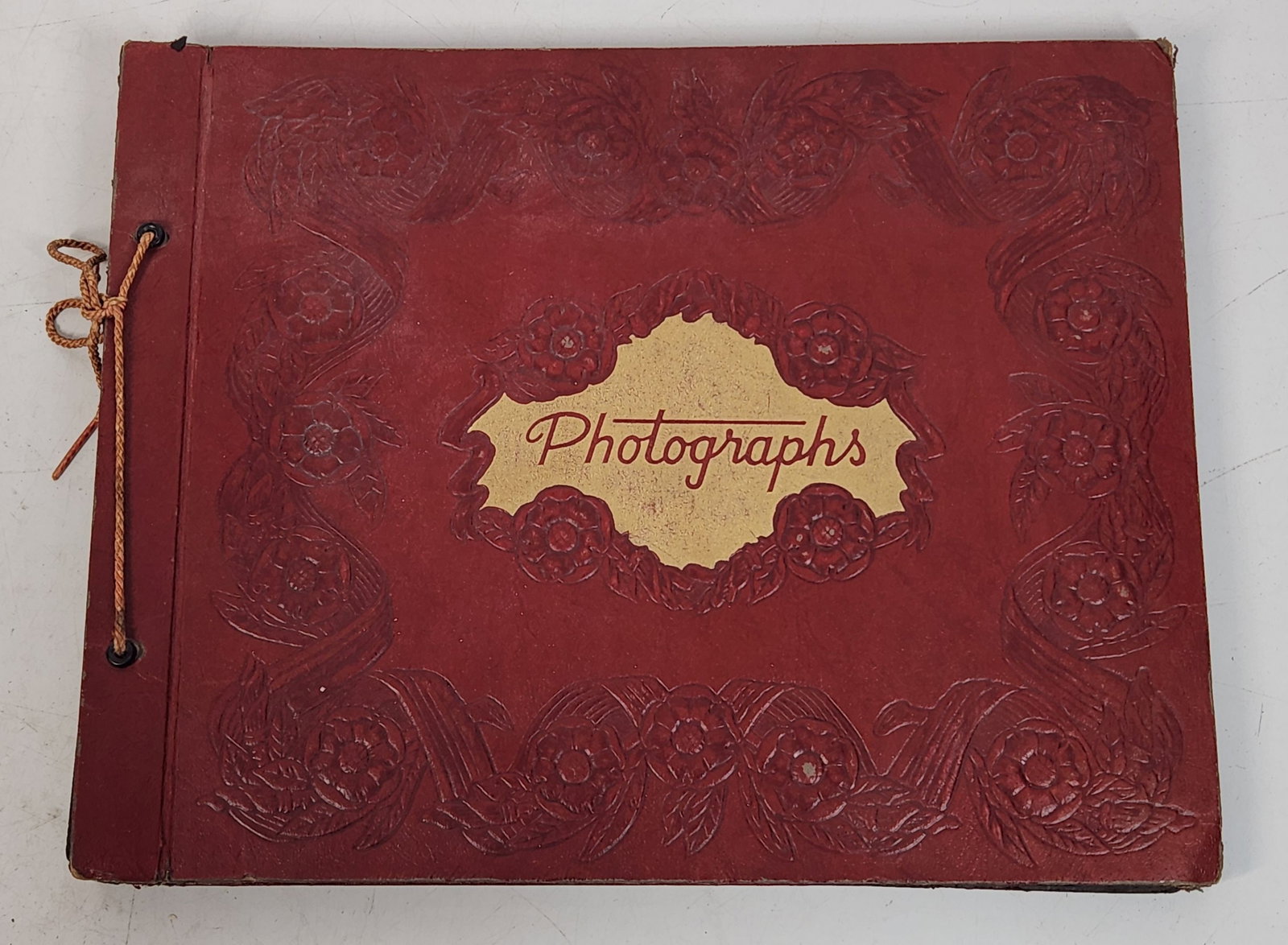 Vintage Photo Album - Floral Embossed Cover - 14"x11": Vintage photo album with red cover. Cover has a floral pattern embossed around the edges. The center of the cover has a gold colored label that reads "Photographs." Album contains numerous black and w