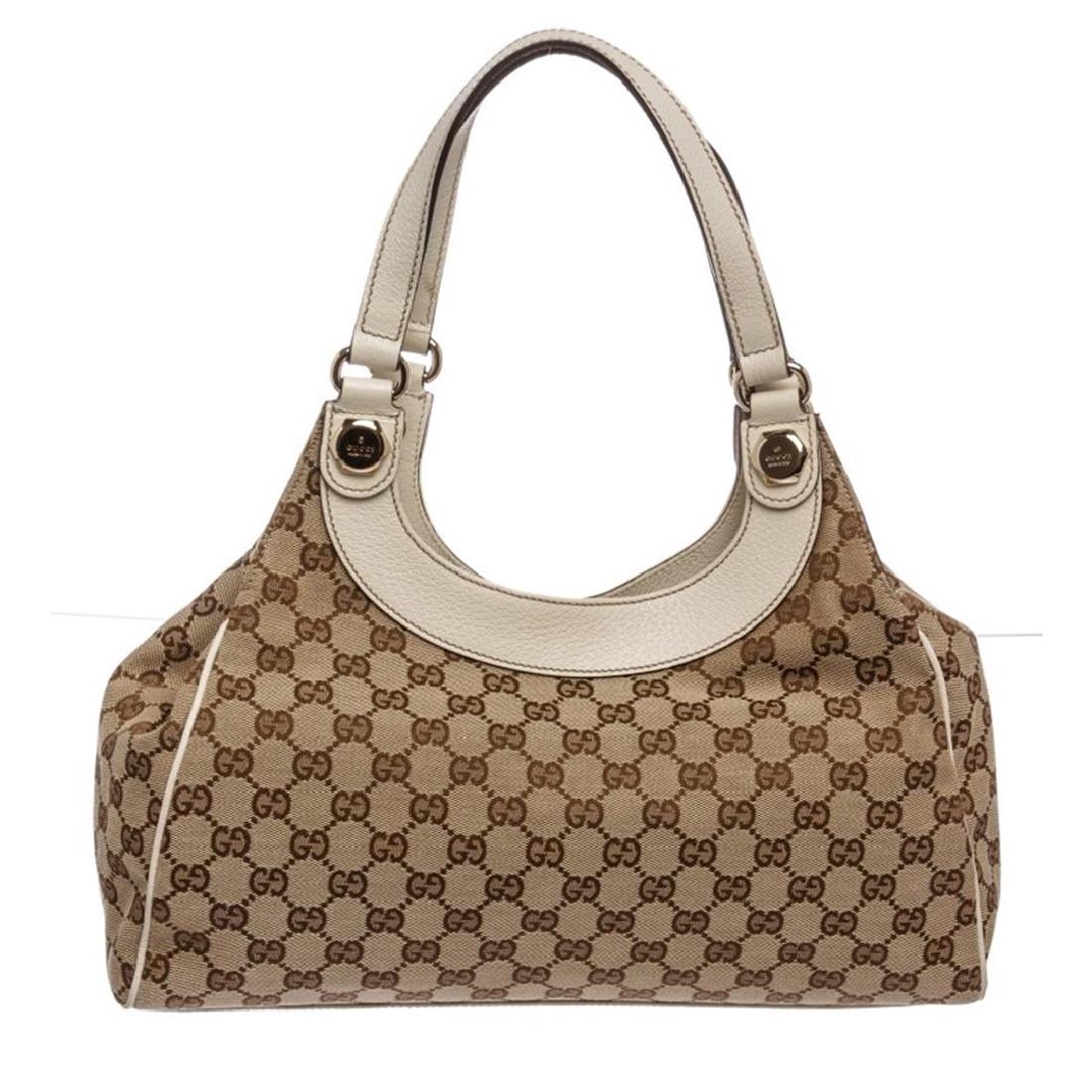 Gucci Brown Monogram Canvas Beige Leather Trim Shoulder: Brown on beige Gucci monogram canvas with beige cowhide trim including piping, gold hardware. Leather trim across the top crest, dual flat handles, with a magnetic snap closure that opens to brown fab