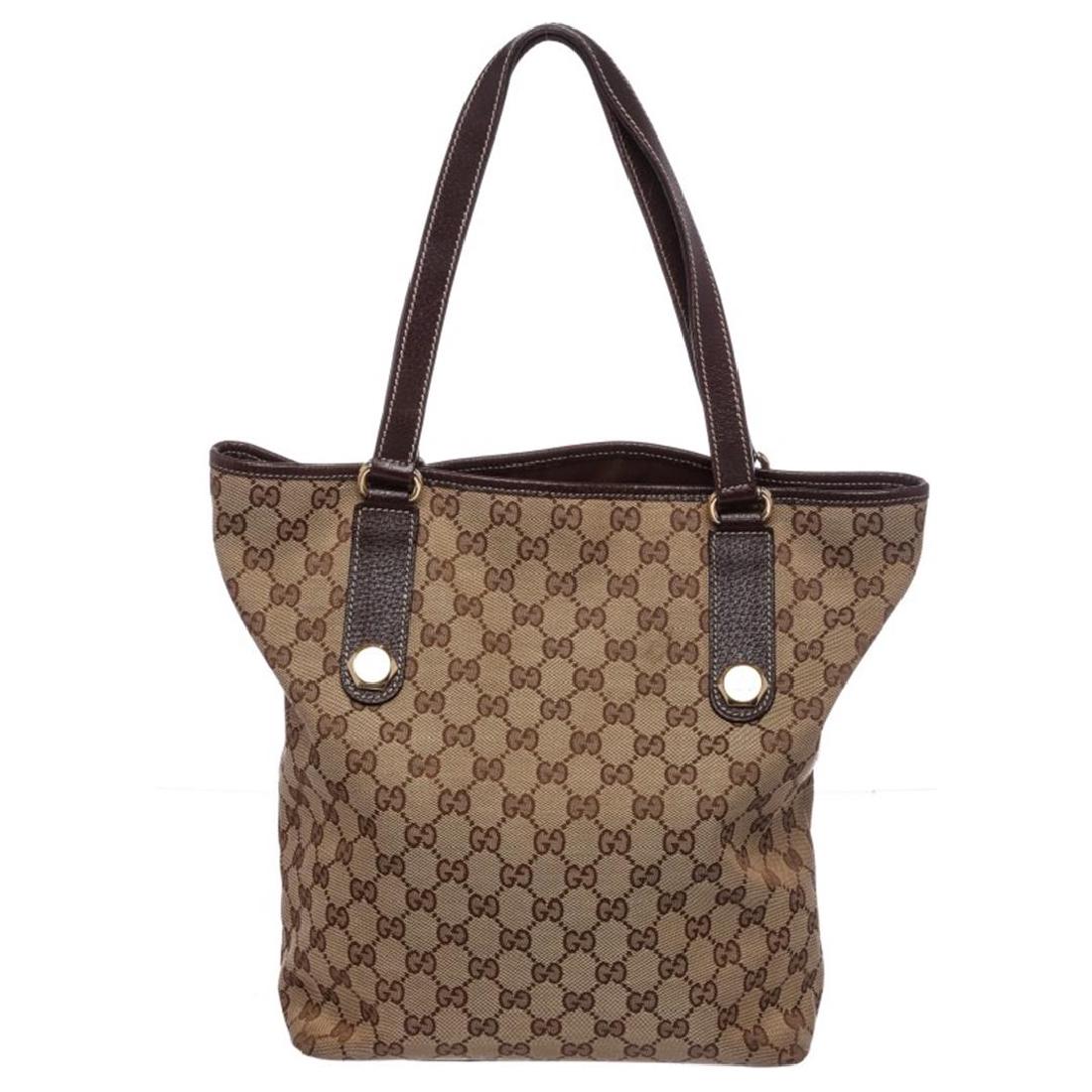 Gucci Brown Canvas Monogram Brown Leather Trim Tote Bag: One Gucci Brown Canvas Monogram Brown Leather Trim Tote Bag. Overall interior is fabric lined with one side zipper pocket and one cell phoneip pocket. Exterior dual flat brown handles leather trim. It