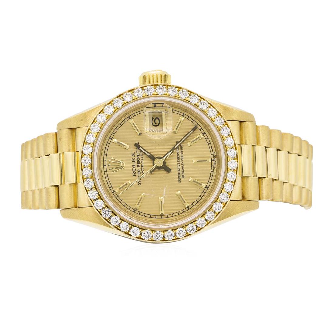 Rolex 18KT Yellow Gold Ladie's Oyster Perpetual: One 18KT yellow gold Rolex ladie's Oyster Perpetual Datejust with a case measuring 26 millimeters with a Rolex diamond bezel, gold dial with stick markers and minute track in black. The case is connec