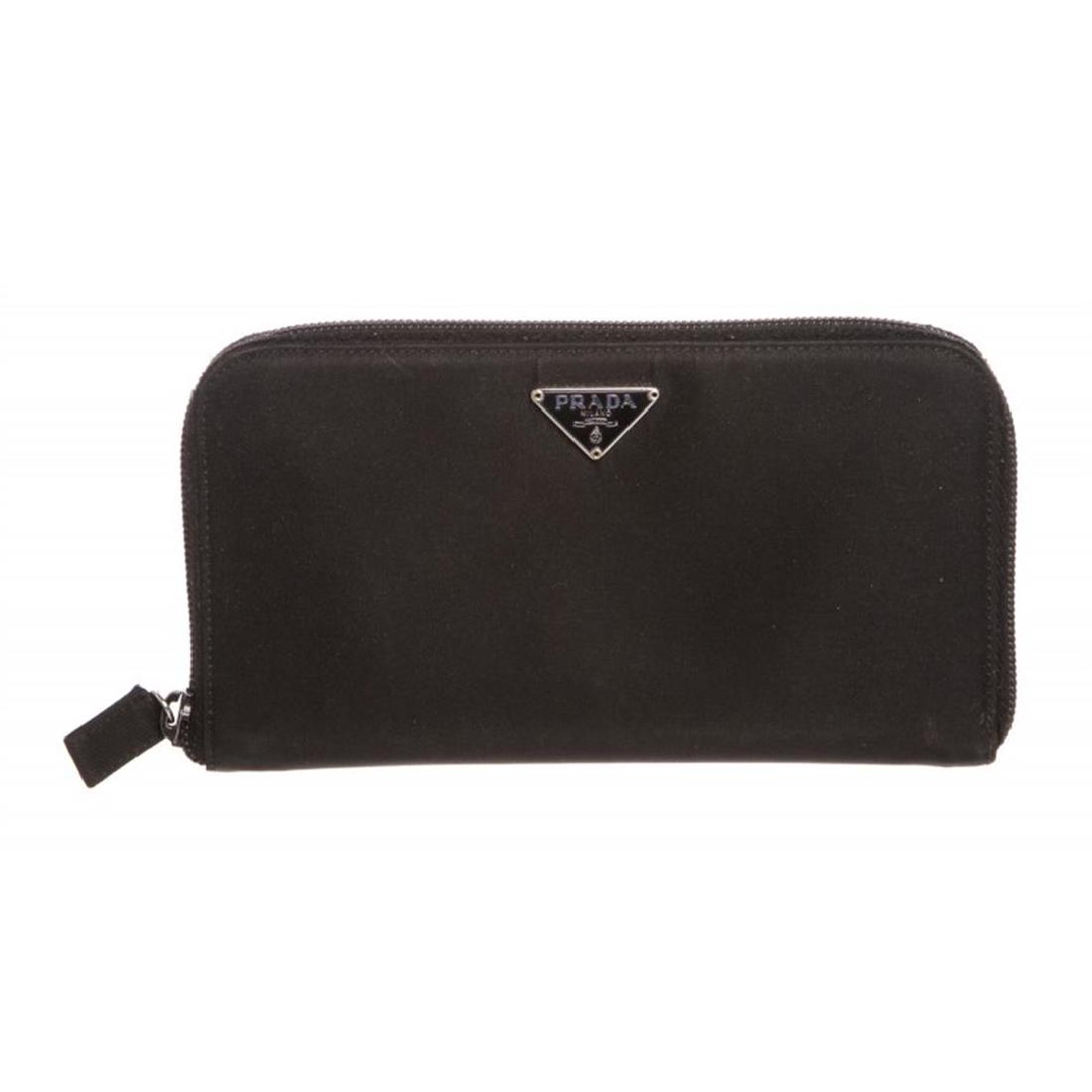 Prada Black Nylon Leather Zipper Wallet: Black Prada nylon leather zipper wallet with black leather lined interior, two side slip pockets, eight card slots, two large open compartments and one large zipper pocket. Item is pre-owned. Item Dim