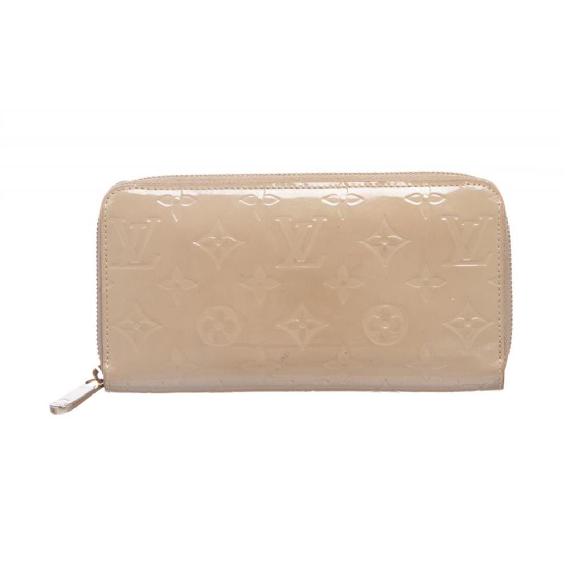 Louis Vuitton Beige Vernis Monogram Zippy Wallet: Monogram Vernis leather Louis Vuitton Zippy wallet with brass hardware, tonal leather lining, four interior compartments; one with zip closure, three bill compartments, eight card slots and zip-around