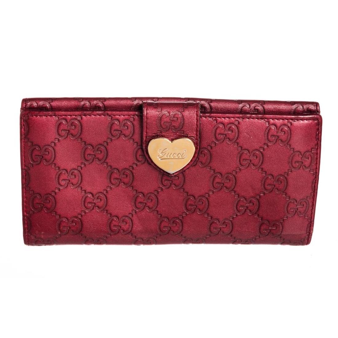 Gucci Metallic Red Guccissima Leather Heart Wallet: Guccissima leather Gucci wallet with gold-tone hardware, single flap pocket with snap closure at back, tonal leather interior, dual bill compartments, dual interior pockets, eight card slots and snap 