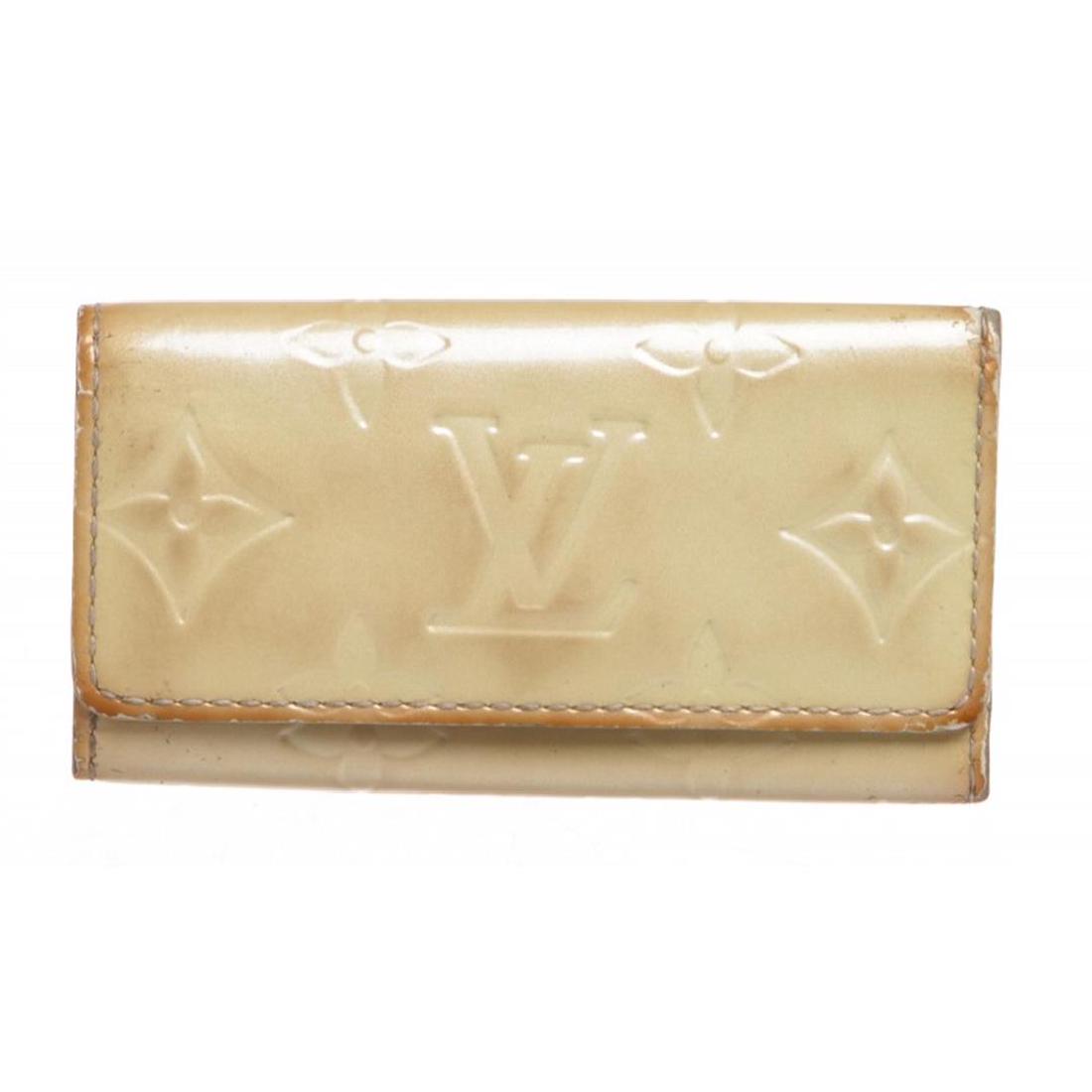Louis Vuitton Beige Monogram Vernis Key Holder: Beige monogram Vernis leather Louis Vuitton key holder with antiqued silver-tone hardware, tonal smooth leather lining, four key hooks at interior wall and snap closure at front flap. Item is pre-owne
