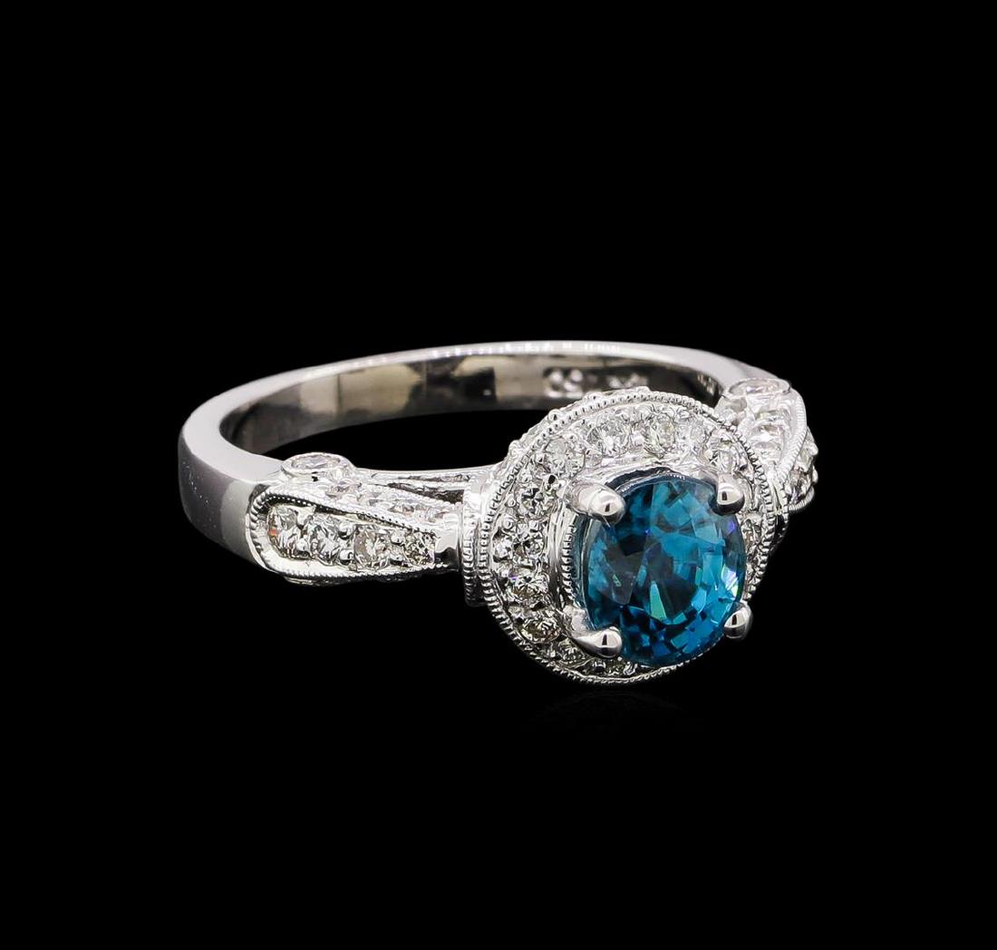 2.16 ctw Blue Zircon and Diamond Ring - 18KT White Gold: One electronically tested 18KT white gold ladies cast blue zircon and diamond ring. The featured blue zircon is set within a diamond bezel supported by a diamond accented under gallery and stylized di