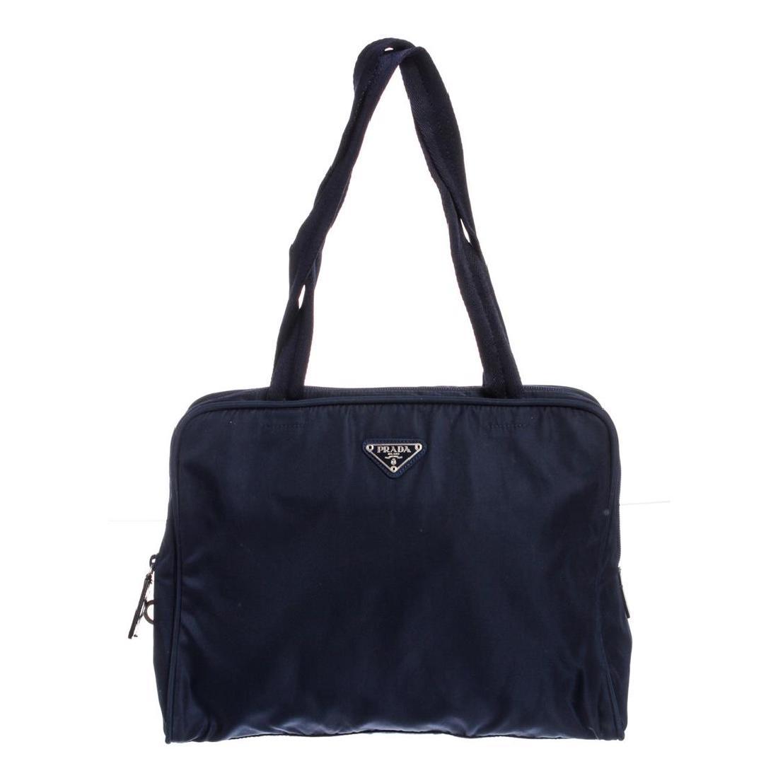 Prada Navy Blue Nylon Double Handle Handbag: Crafted out of navy blue nylon, silver-tone hardware, and zip top closure. Inner fabric lining and one side zip pocket.