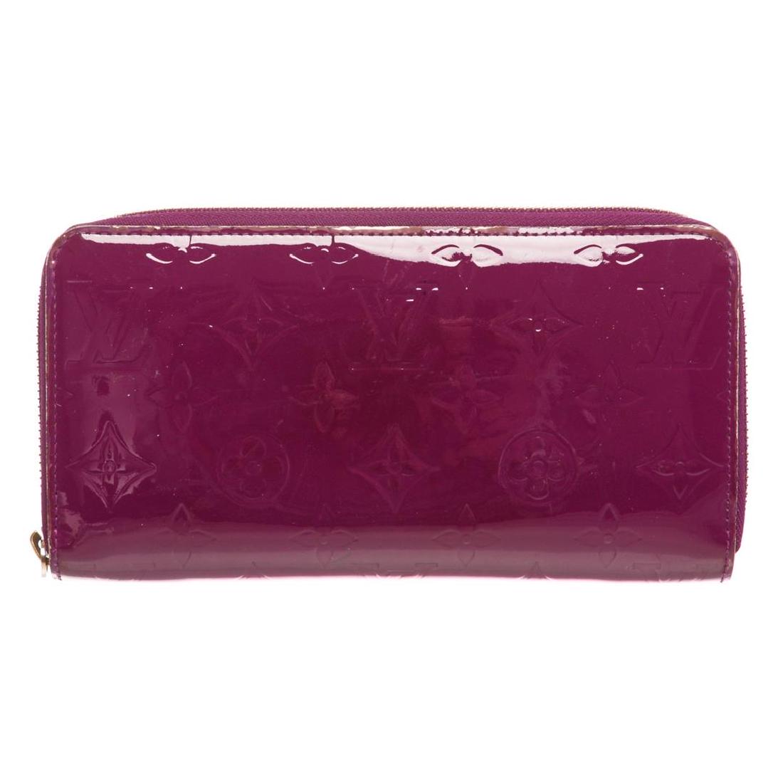 Louis Vuitton Purple Vernis Monogram Zippy Wallet: Monogram Vernis leather Louis Vuitton Zippy wallet with brass hardware, tonal leather lining, four interior compartments; one with zip closure, three bill compartments, eight card slots and zip-around