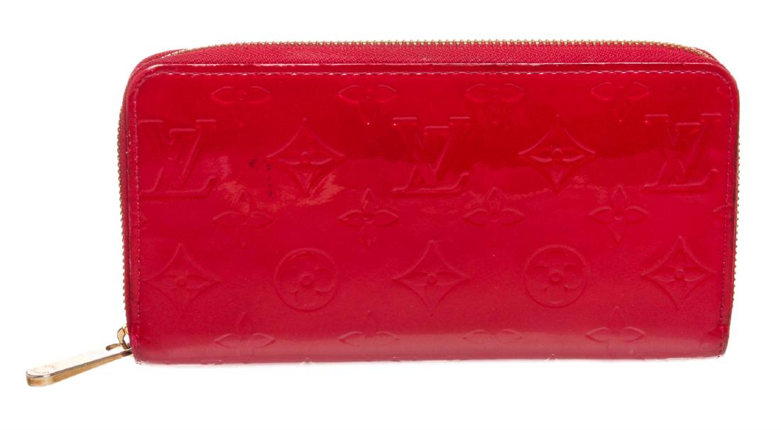 Louis Vuitton Red Vernis Monogram Zippy Wallet: Monogram Vernis leather Louis Vuitton Zippy wallet with gold-tone hardware, tonal leather lining, four interior compartments; one with zip closure, three bill compartments, eight card slots and zip-ar