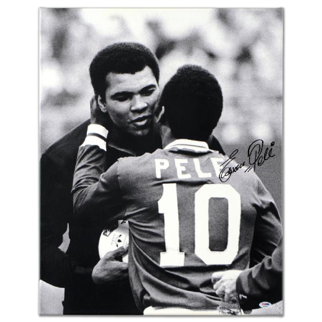 Pele & Ali Hug by Pele: "Pele & Ali Hug" is a gallery wrapped print on canvas that is autographed by legendary Brazilian footballer, Pele! This piece was authenticated by PSA/DNA, which authenticates sports memorabilia using
