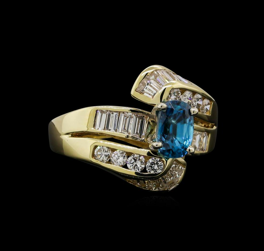 2.17 ctw Blue Zircon and Diamond Ring - 14KT Yellow: One electronically tested 14KT yellow gold ladies cast & assembled blue zircon and diamond ring with a bright polish finish. The featured blue zircon is set within bypassing diamond ribbons supported 